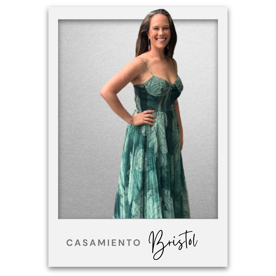 Mujer sonriendo, vestida con un vestido largo de estampado en tonos verdes, en un fondo gris claro, con borde blanco y texto que dice 'CASAMIENTO Bristol'. Bristol Baughan