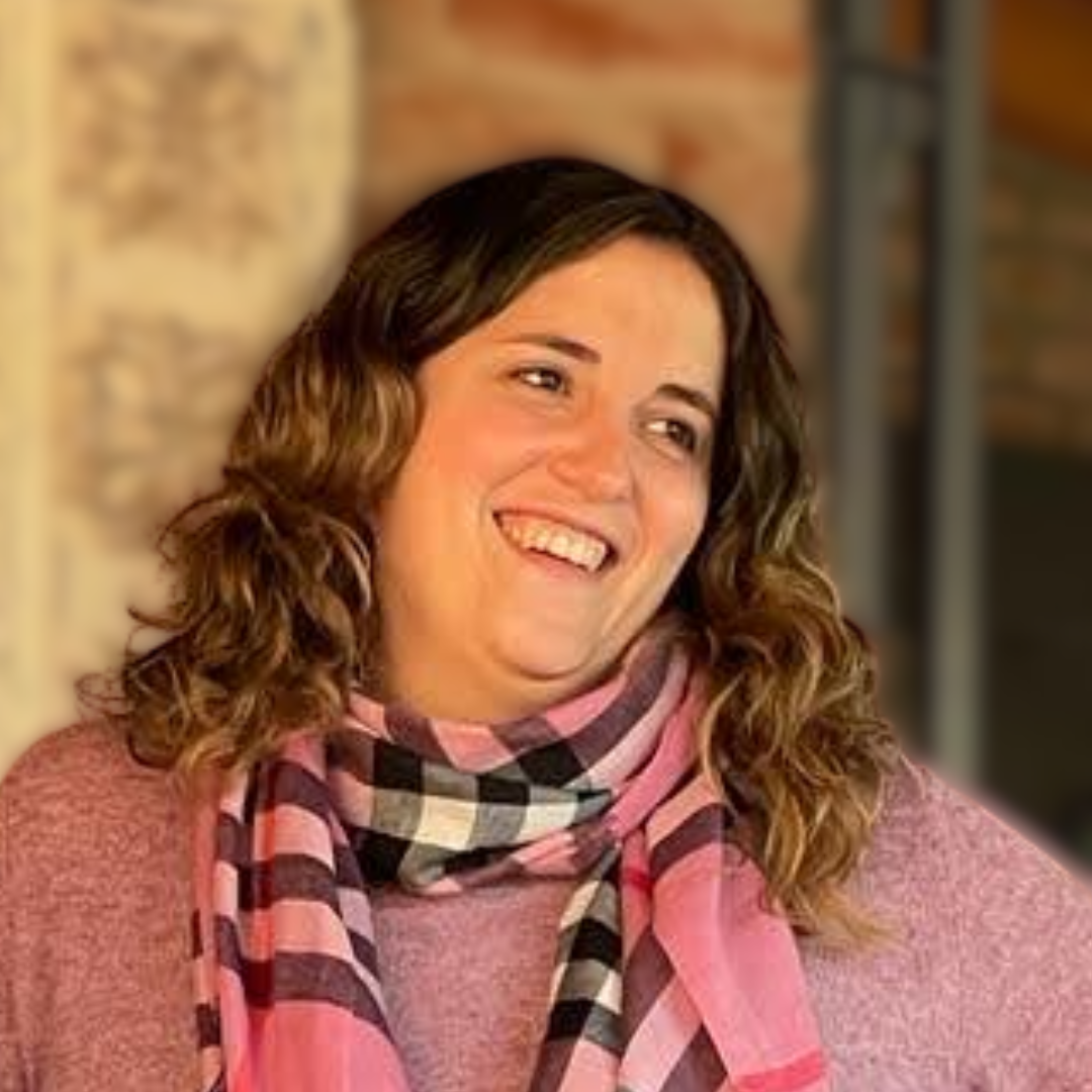 Mujer sonriendo con pelo castaño rizado y bufanda a cuadros en un entorno interior