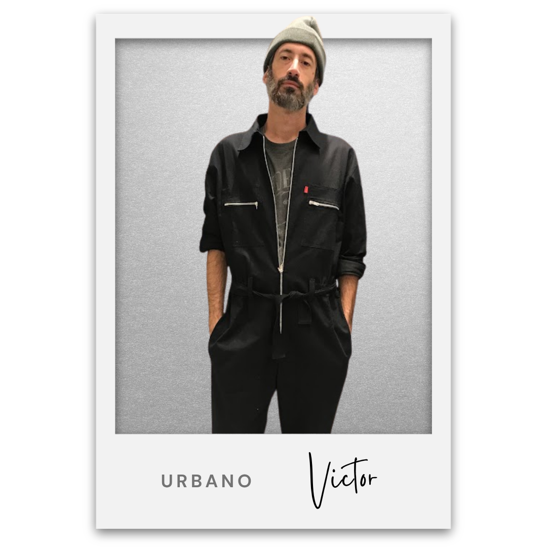Un hombre con barba y bigote, lleva un gorro gris y ropa negra, posando con las manos en los bolsillos en un fondo gris, en una imagen de estilo Polaroid con la palabra "Urbano" y el nombre "Víctor" en la parte inferior. Victor Mochkofsky