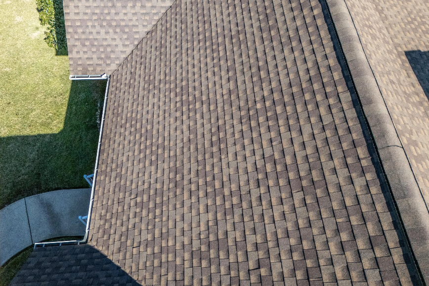homeowner cleaning roof gutters as part of roof maintenance