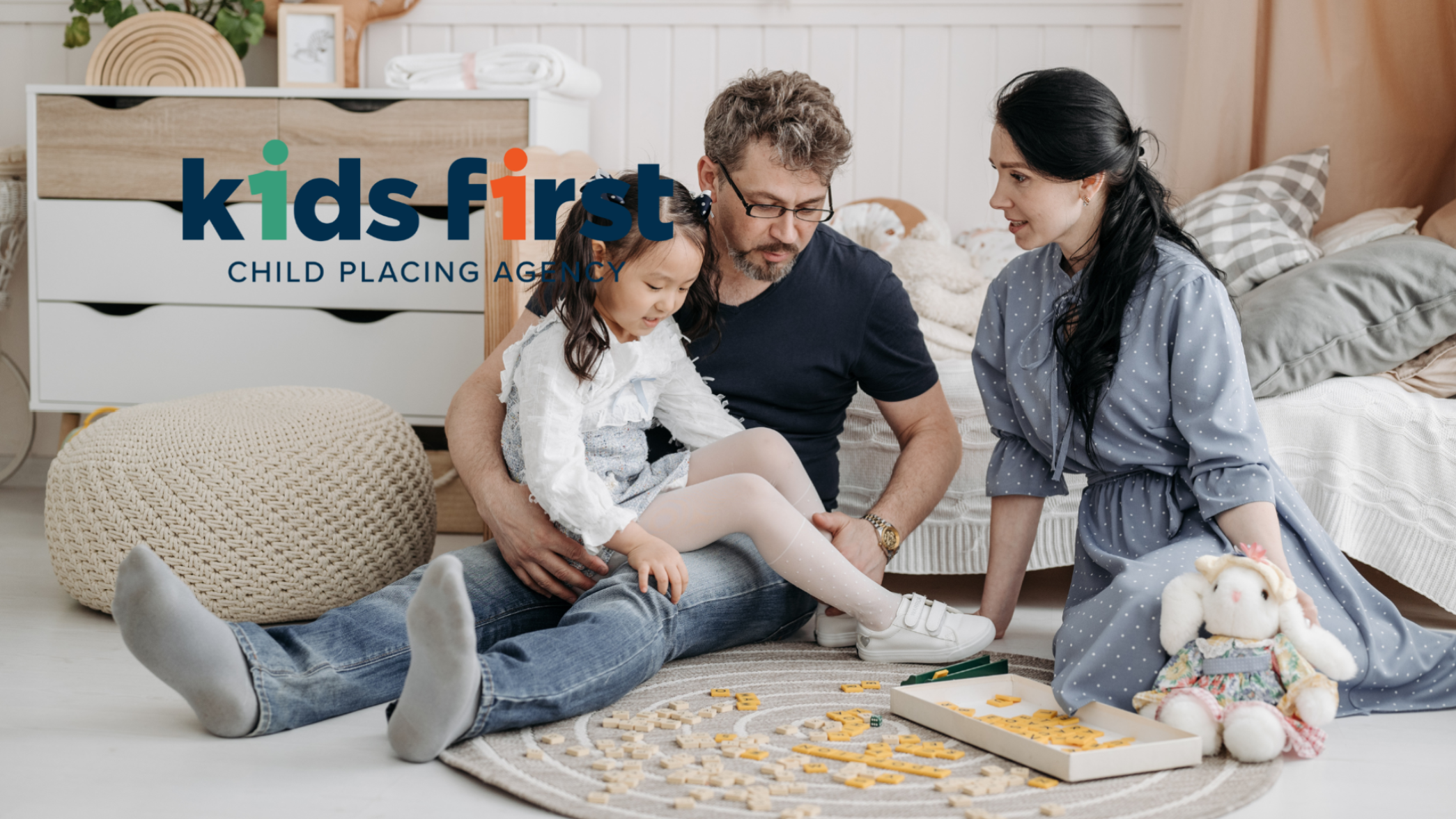 Foster family playing letter tile game on the floor with their young daughter, Kids First foster parenting family in Texas