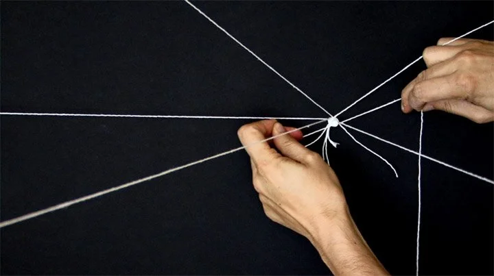 Two hands pulling white strings in a web