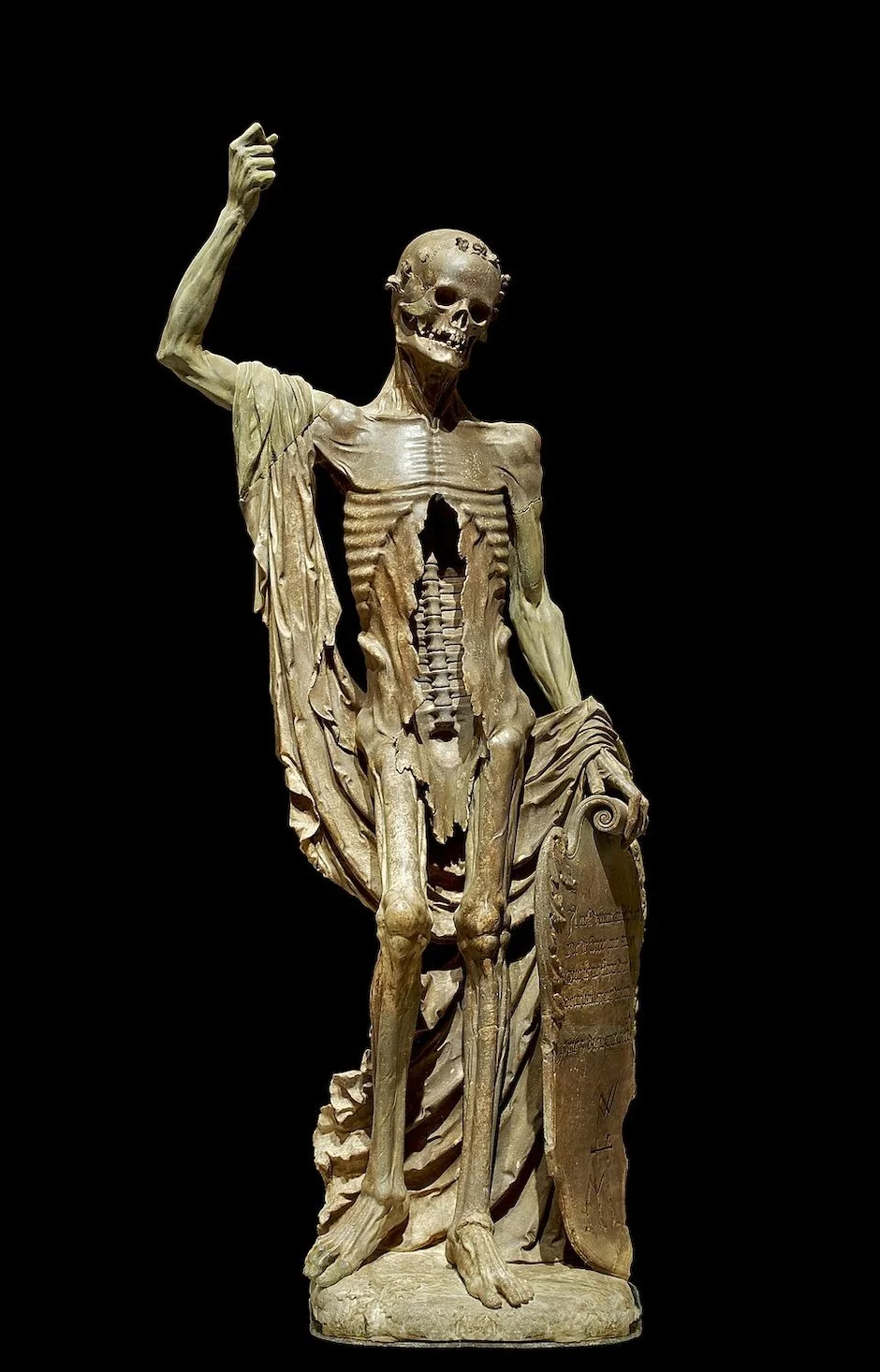 Alabaster statue of a standing skeleton with right arm raised and fist clinched