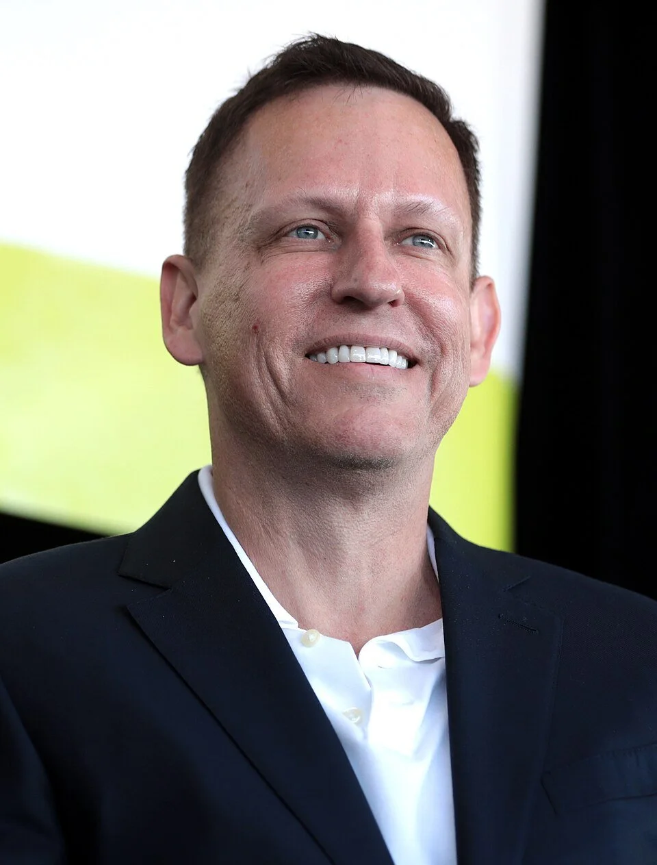 Smiling man gazing into distance against a yellow and white backdrop