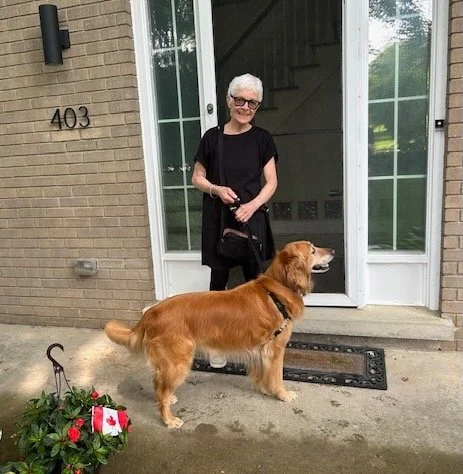 White-haired woman and alert Golden Retriever at front door of house