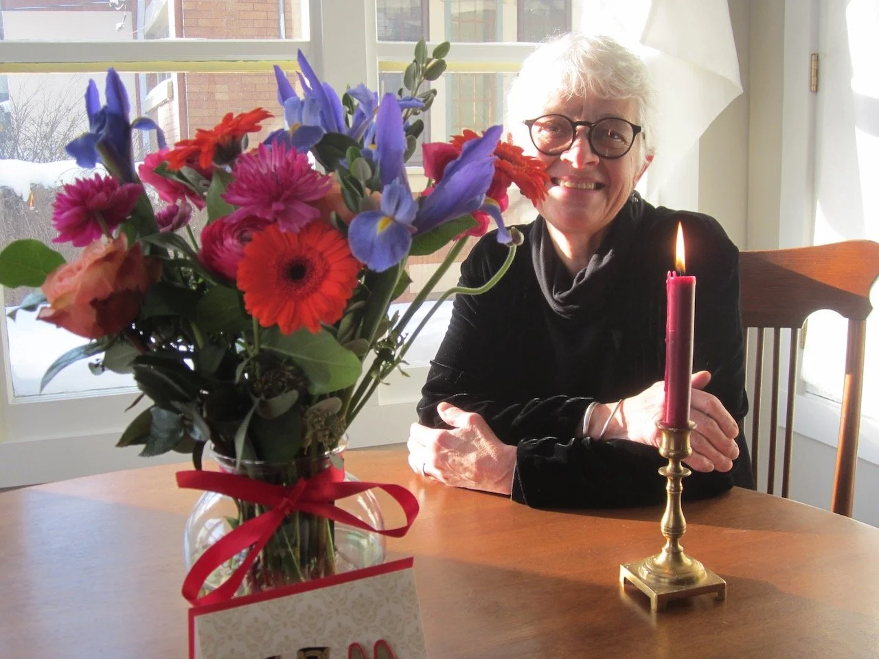 Seated smiling woman with floral bouquet and lighted candle