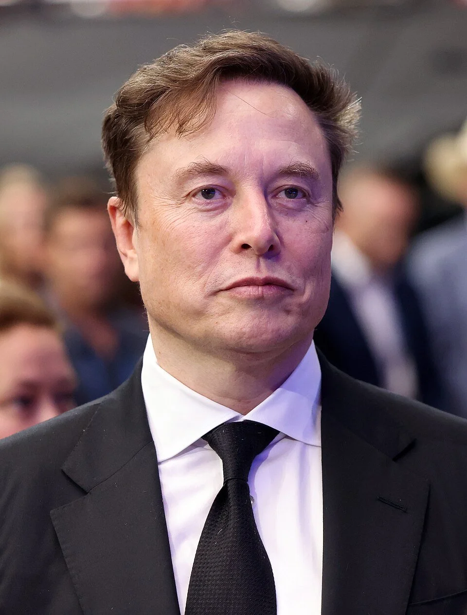 Man wearing a black coat and tie and staring into distance