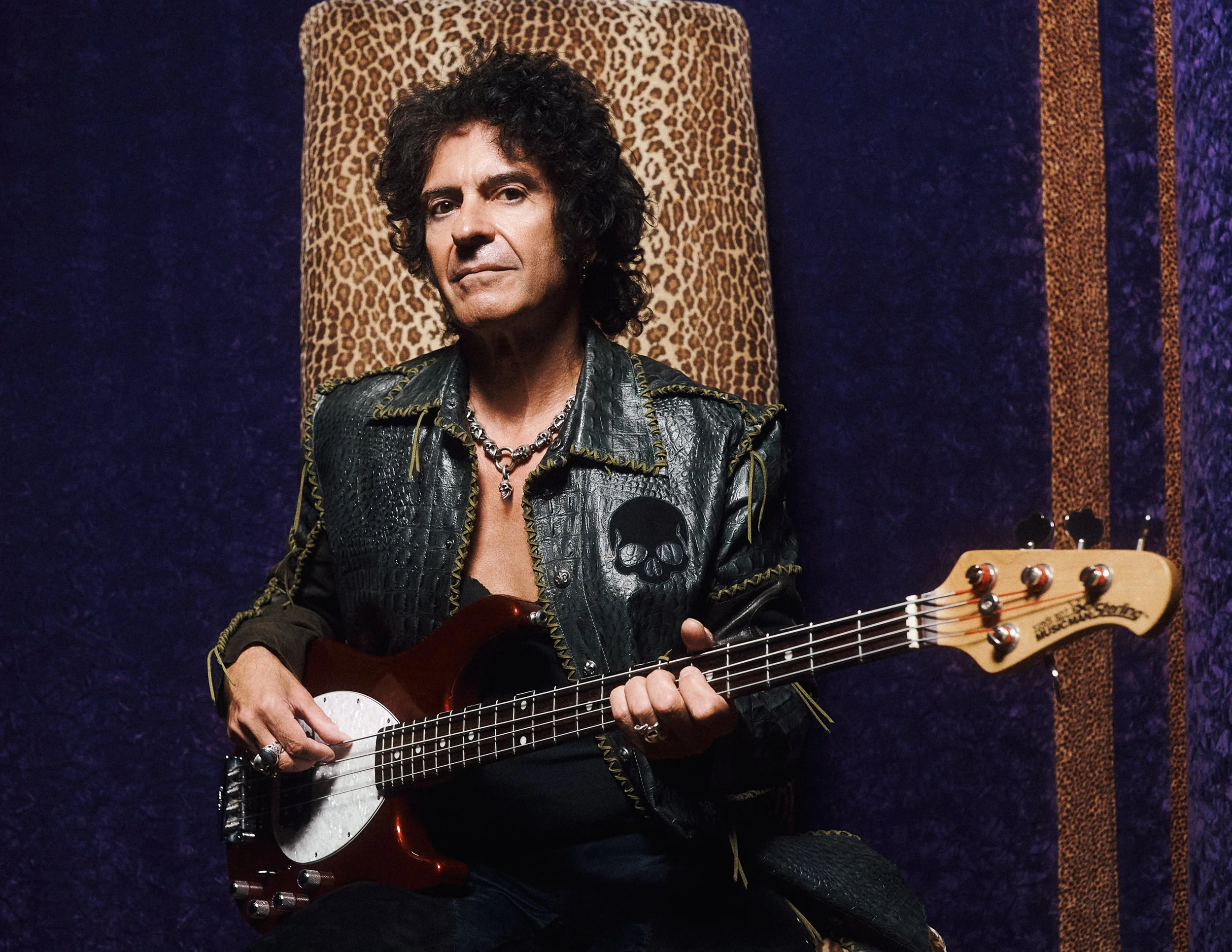 Studio portrait of Phil Soussan holding bass guitar, reflecting his iconic presence as a legendary rock musician and songwriter.