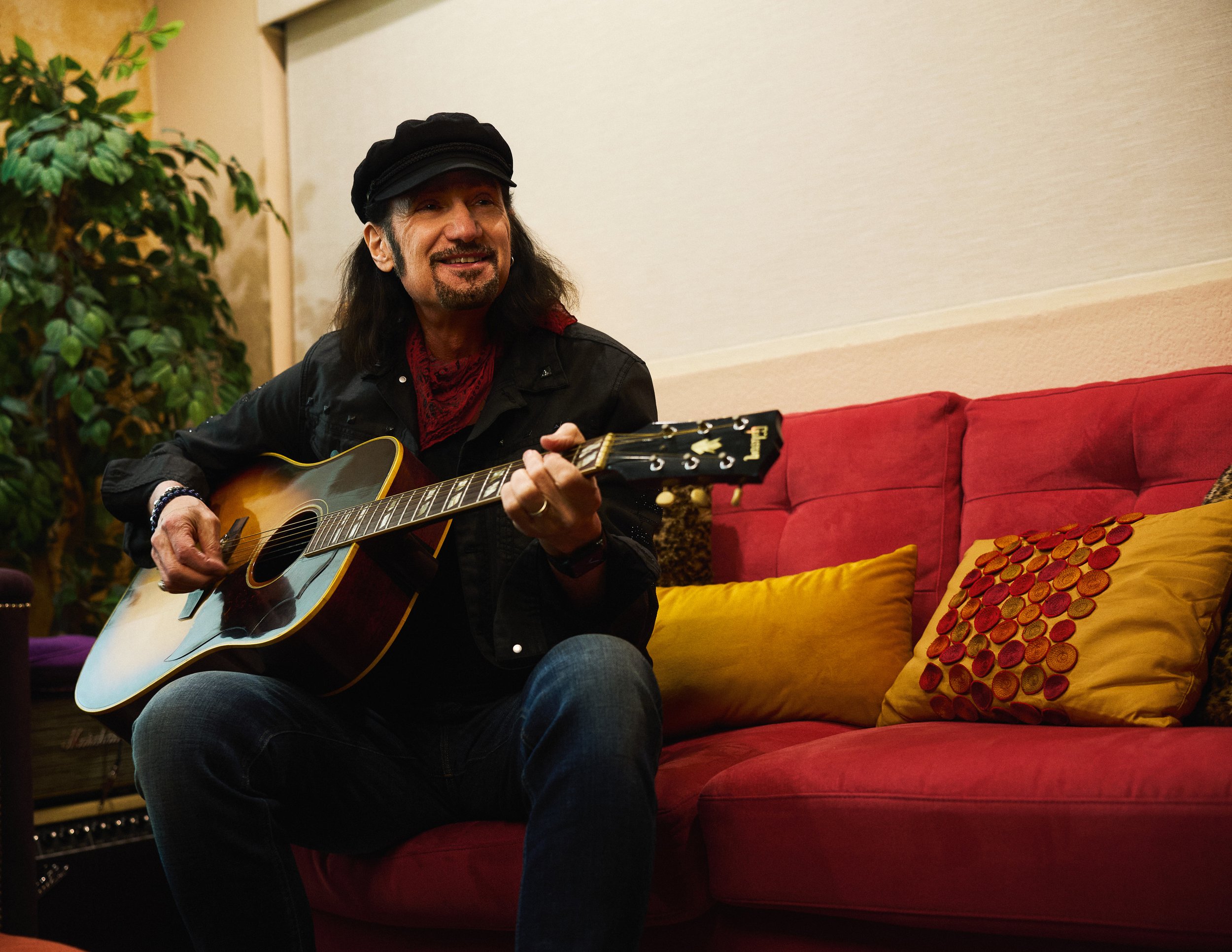 Bruce Kulick photographed with acoustic guitar, highlighting his versatility beyond electric rock performance