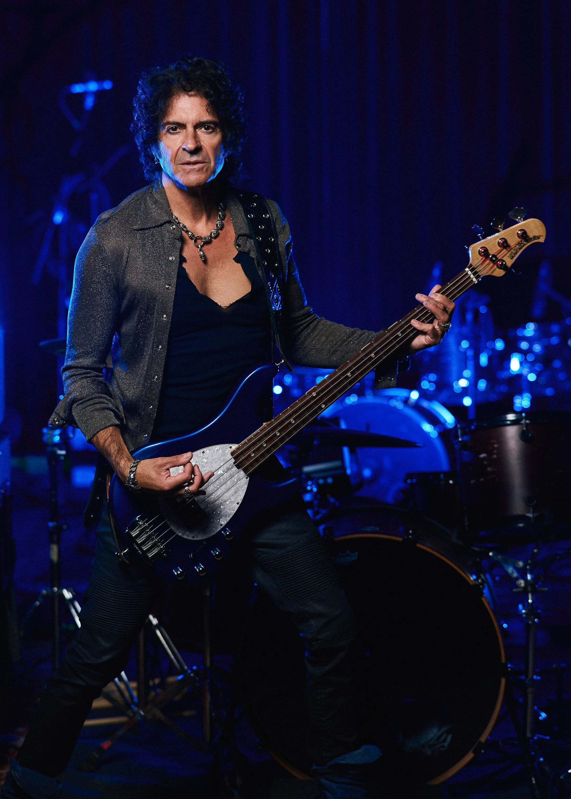 Studio portrait of Phil Soussan, iconic rock bassist and songwriter, captured holding his bass guitar in a cinematic professional portrait.