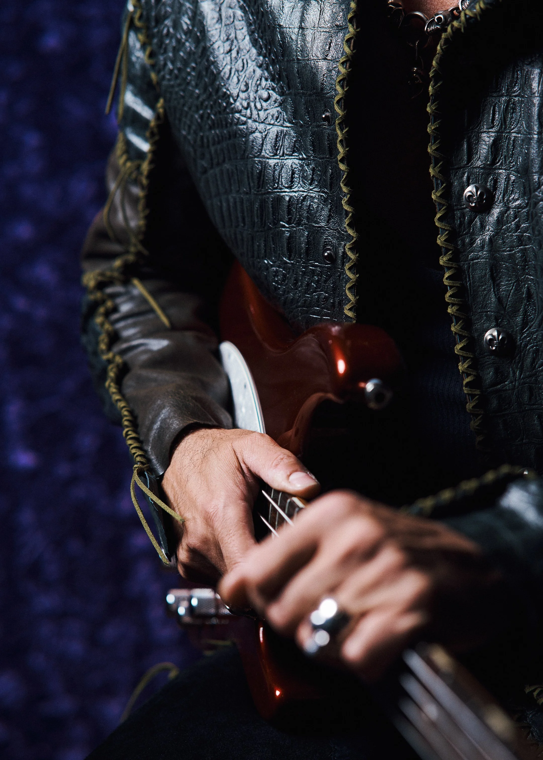 Detail portrait highlighting Phil Soussan holding his bass guitar, emphasizing his identity as a legendary bassist and rock musician.