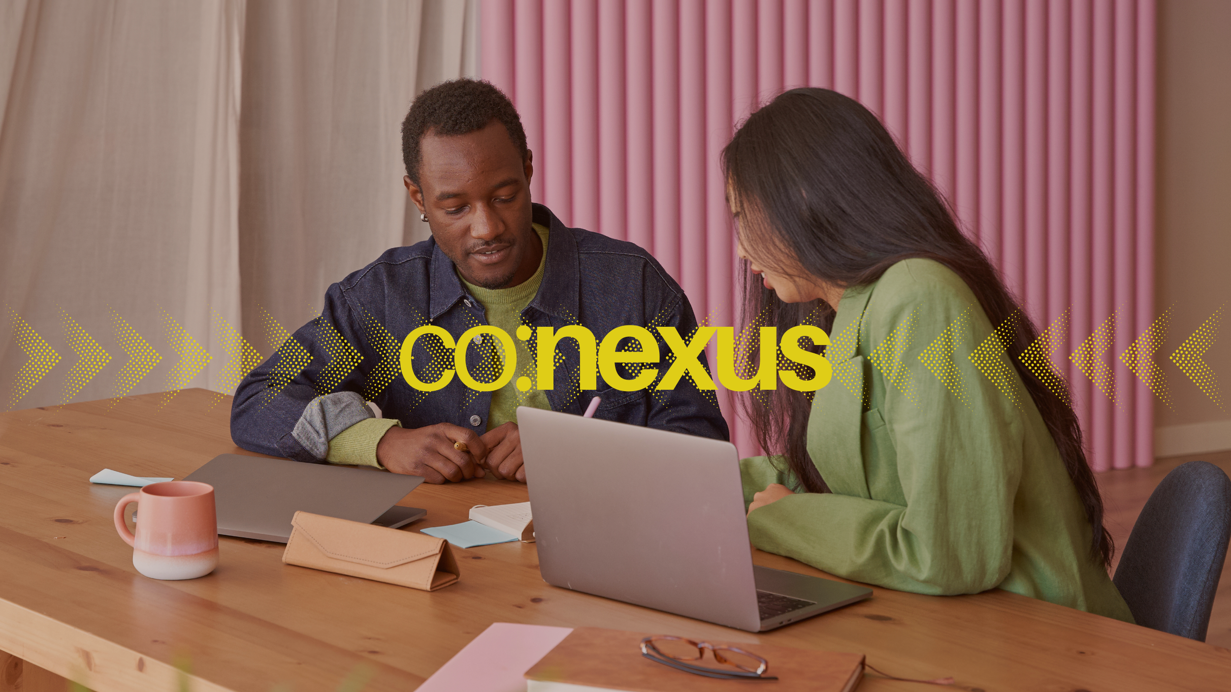 Two people working on a laptop together at a co:nexus event