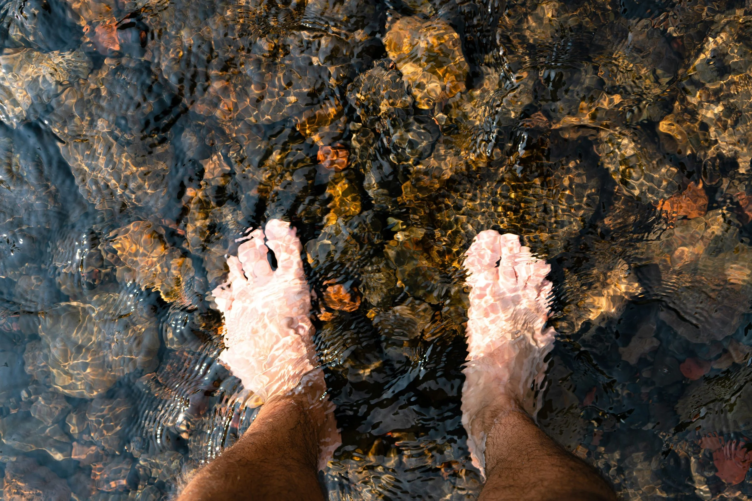 feet in water with stones beneath