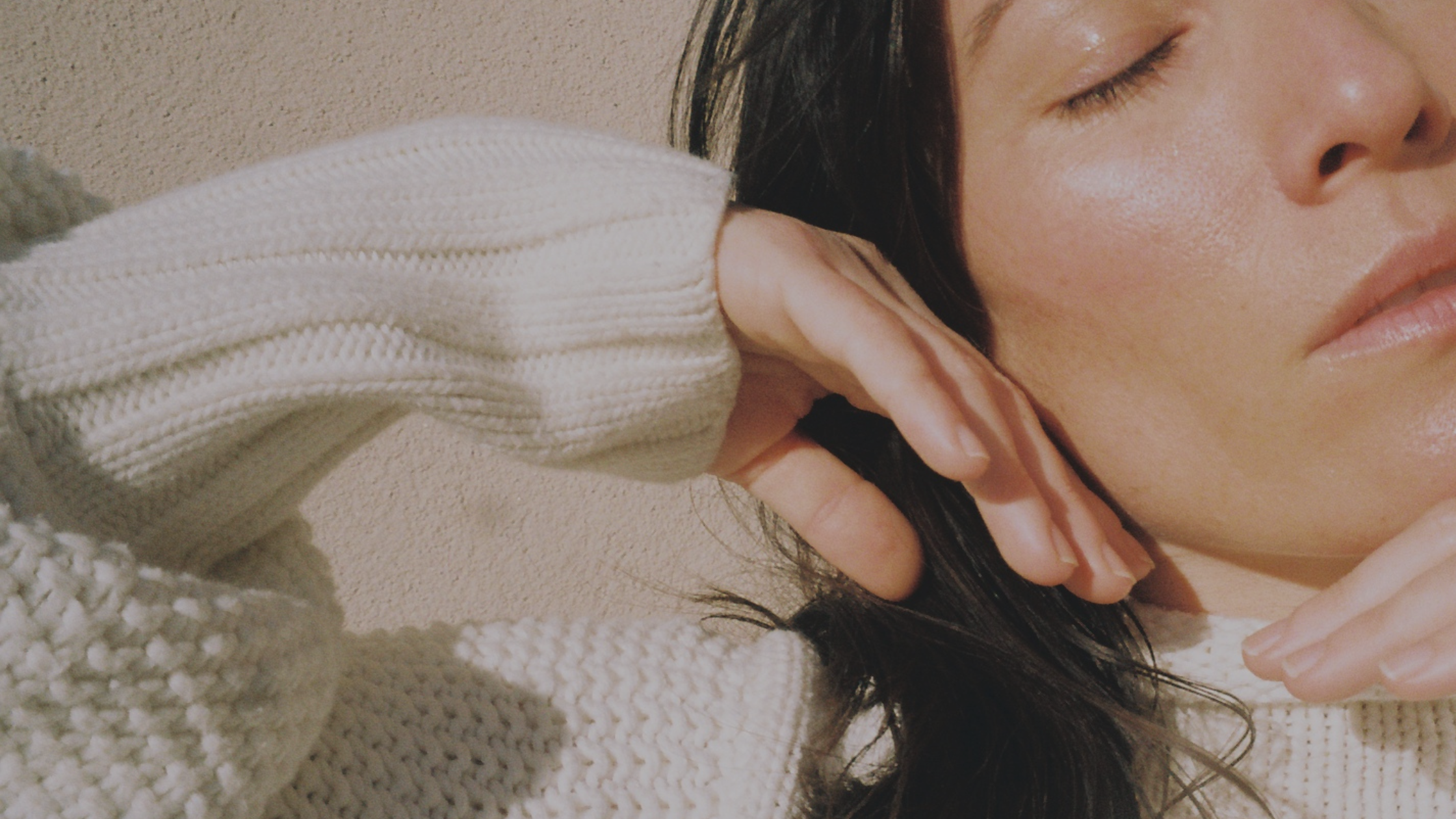 Close-up of women's face, eyes closed, and hand to cheek