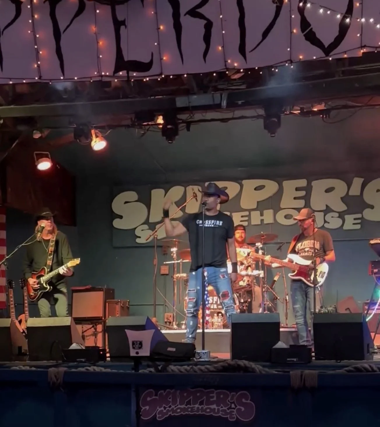 Band performing on stage at Skipper's Smokehouse, featuring a singer in a cowboy hat and musicians playing guitar and drums.