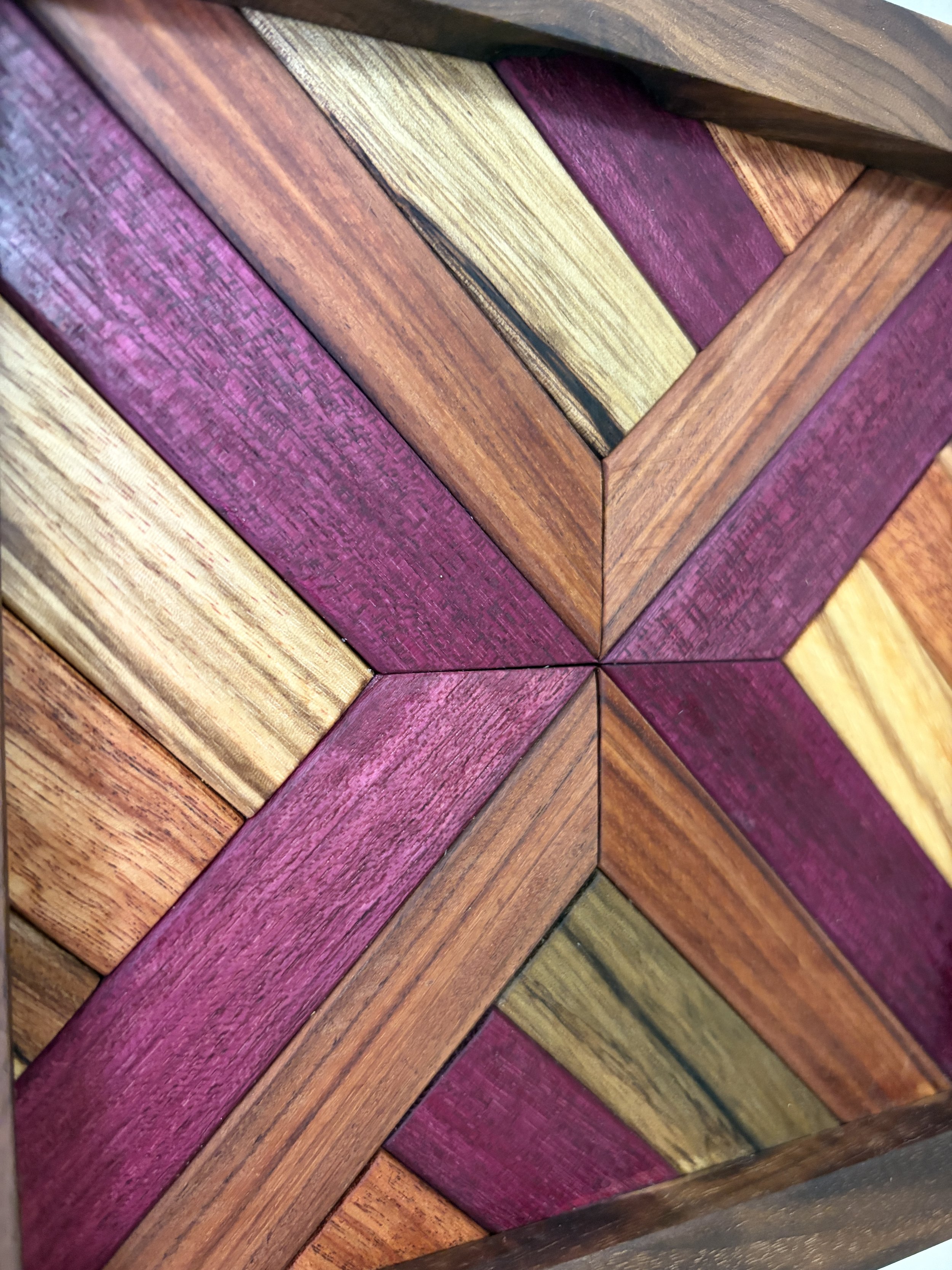 Close up view of a handcrafted framed wooden mosaic made from various exotic woods.