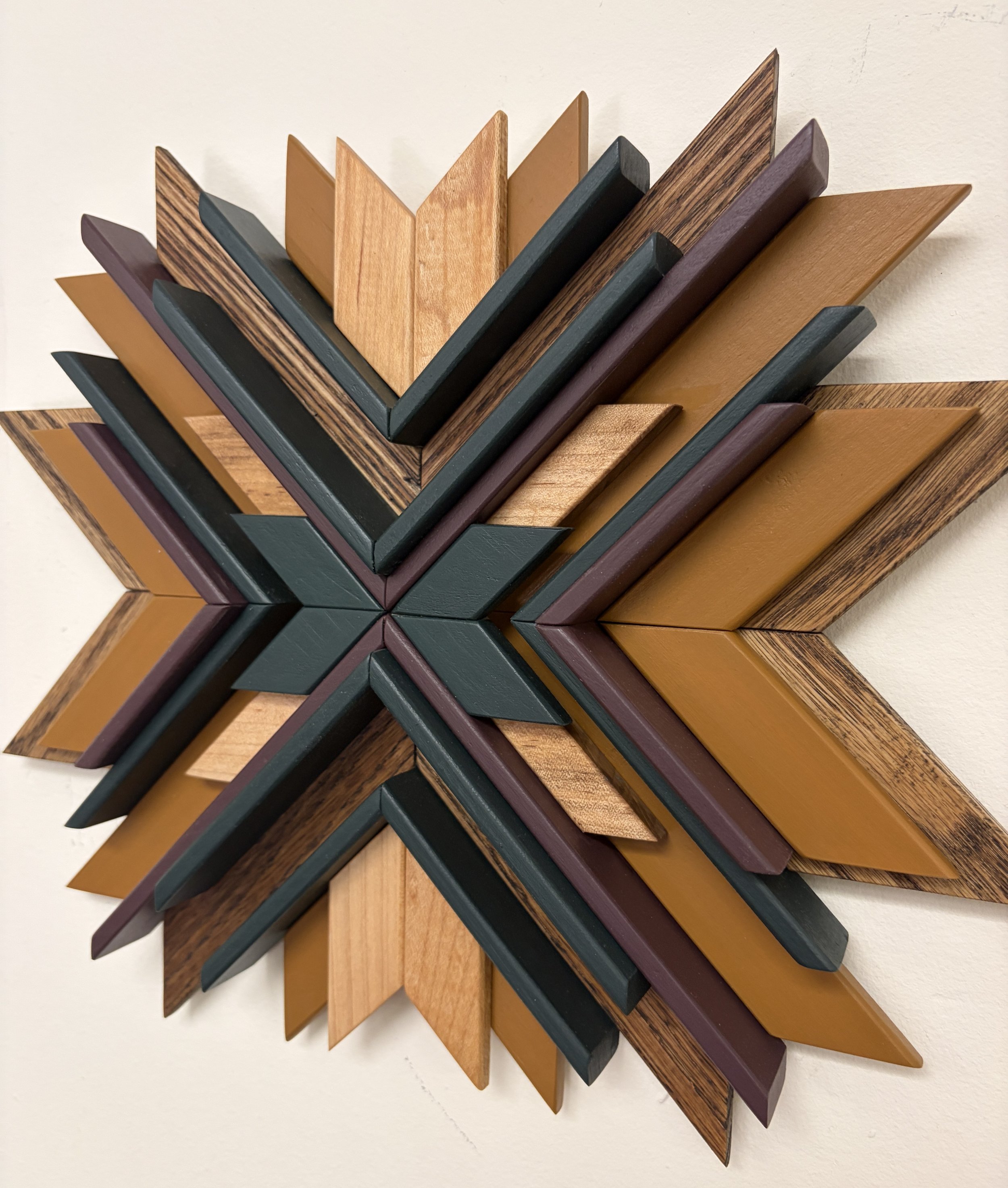 Side view of a wooden sunburst style mosaic in purple, green, and yellow paint with natural and espresso stains.