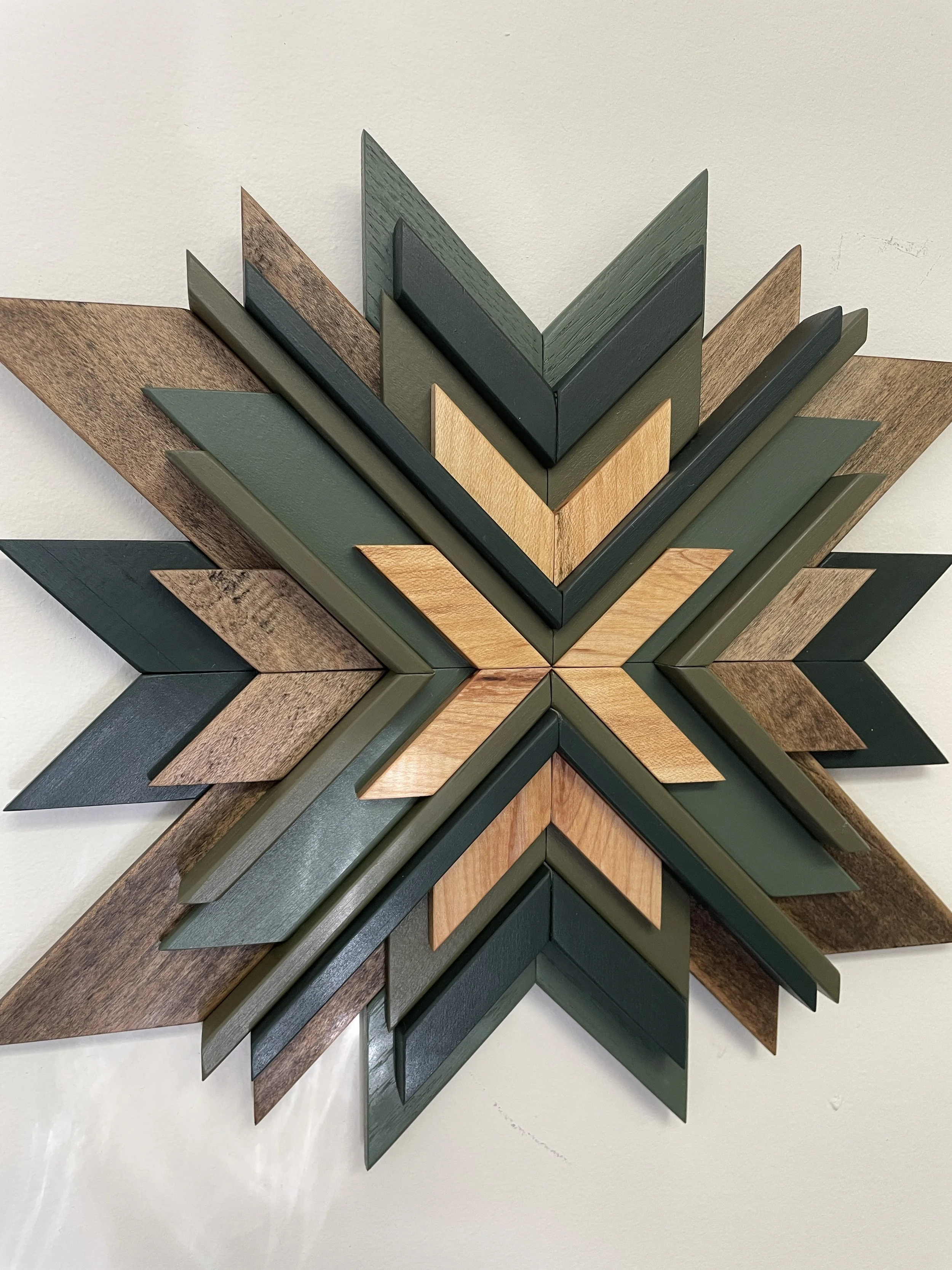 Angled view of a handcrafted wooden mosaic with a sunburst design in black paint with natural and espresso wood stains.