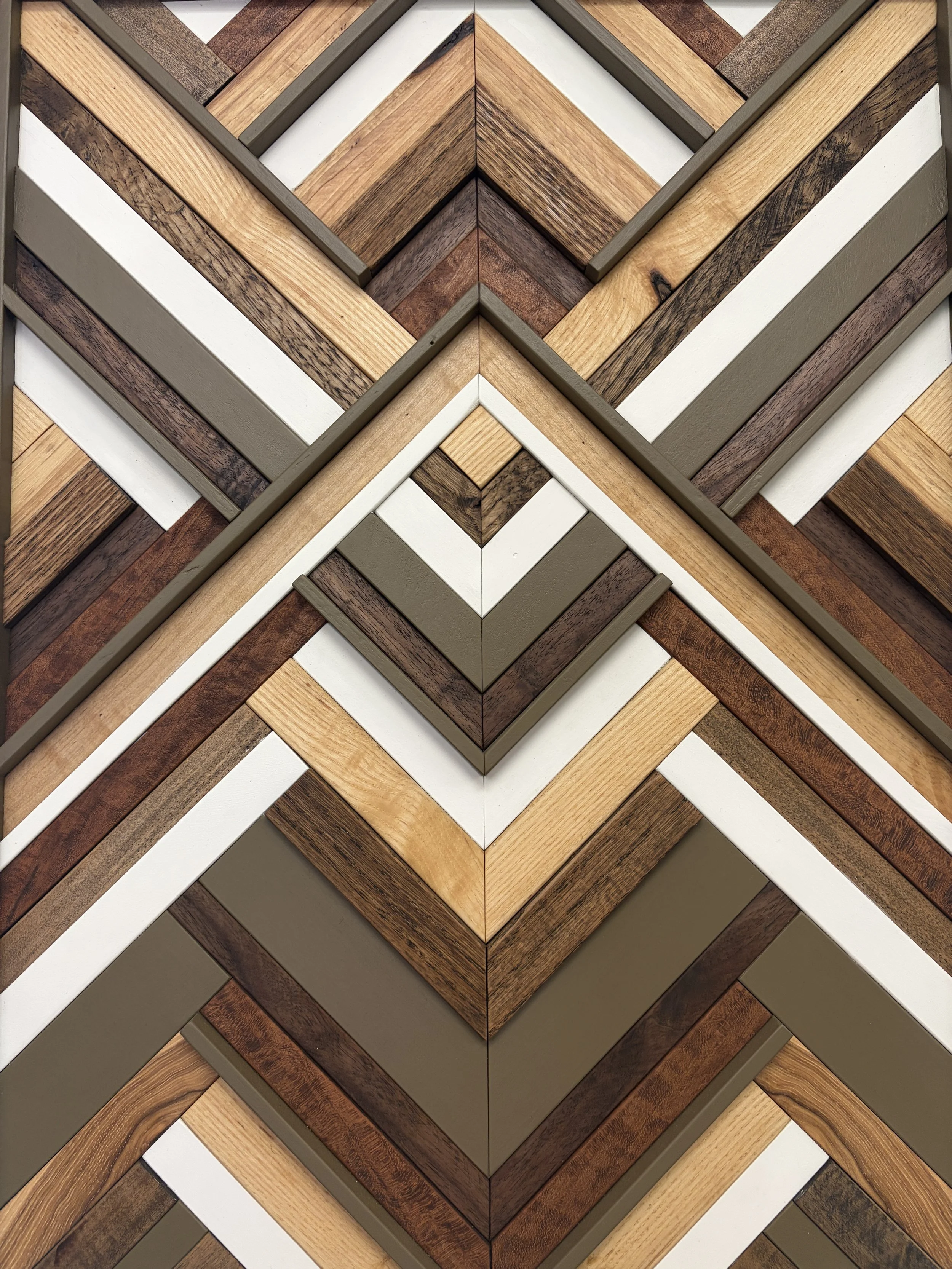 Zoomed in view of a handcrafted framed wooden mosaic in white and light olive green paint with natural, espresso, and red mahogany stains.