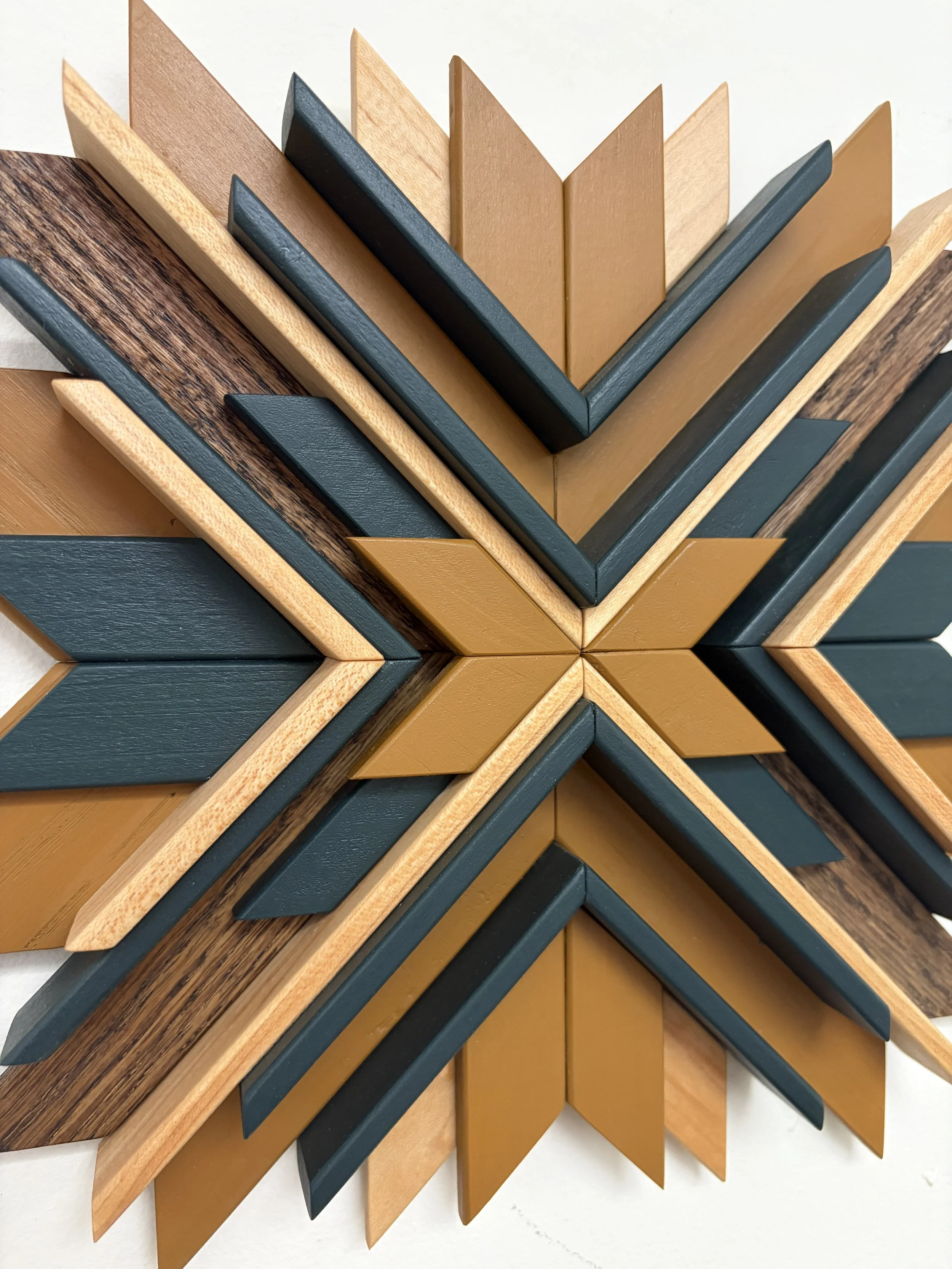 Close up view of a wooden sunburst style mosaic in green and yellow paint with natural and espresso stains.