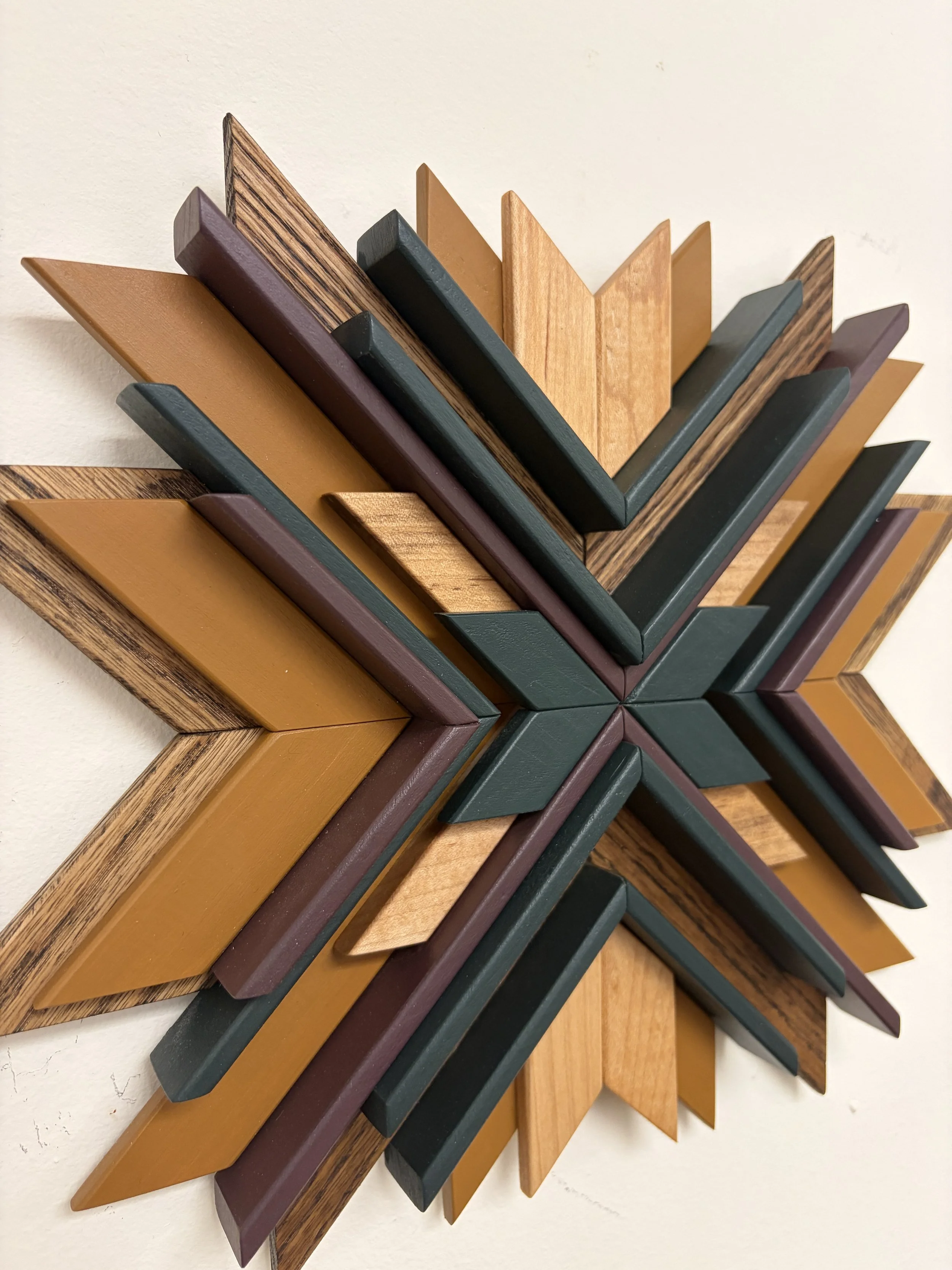 Angled view of a wooden sunburst style mosaic in purple, green, and yellow paint with natural and espresso stains.