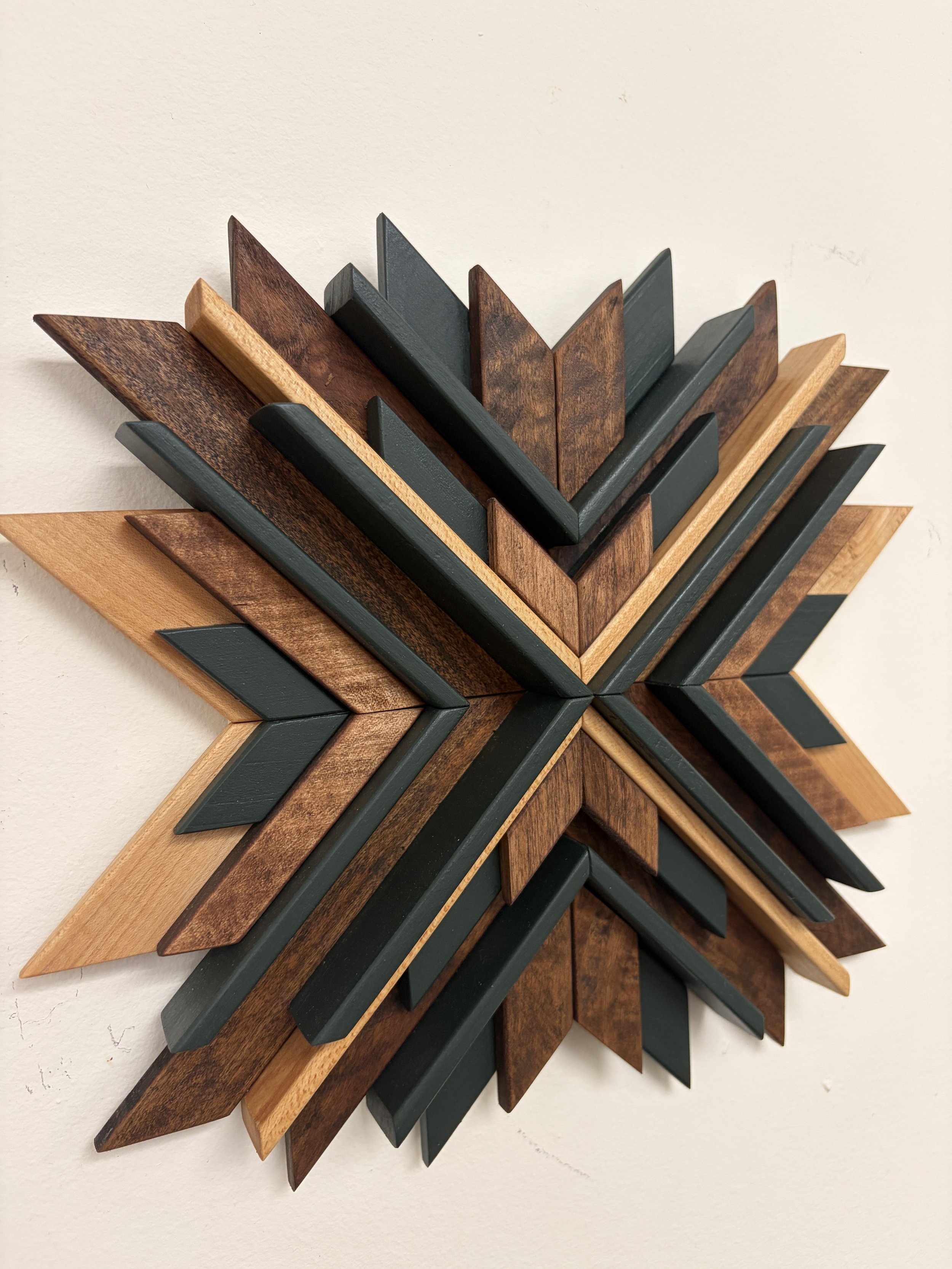 Side view of a wooden sunburst style mosaic in green paint with light and dark stains.
