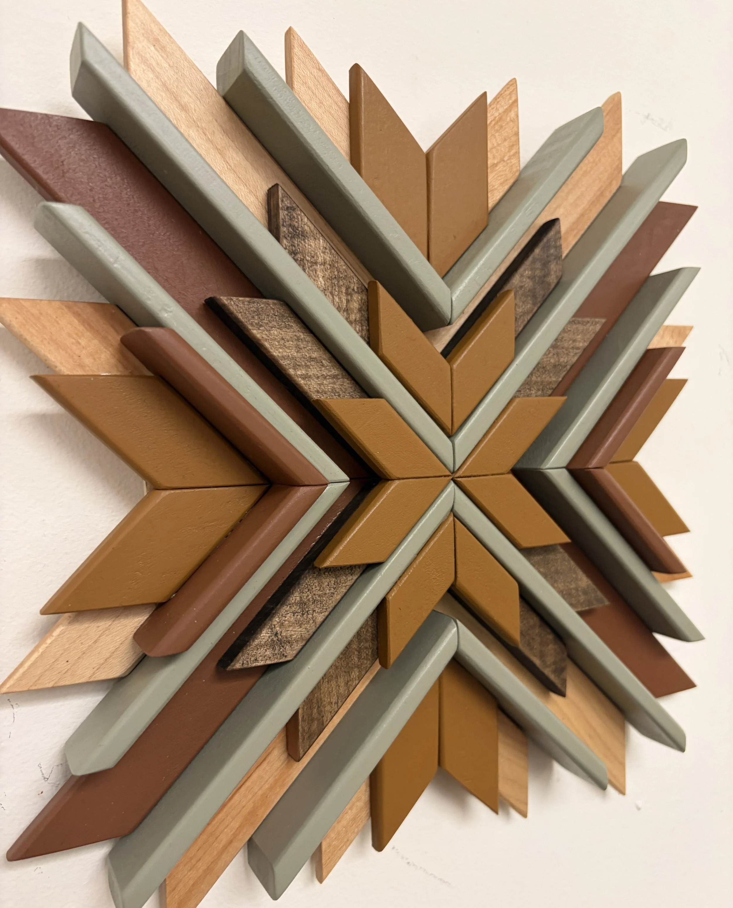 Angled view of a wooden sunburst style mosaic in green, yellow, and orange paint with natural and espresso stains.