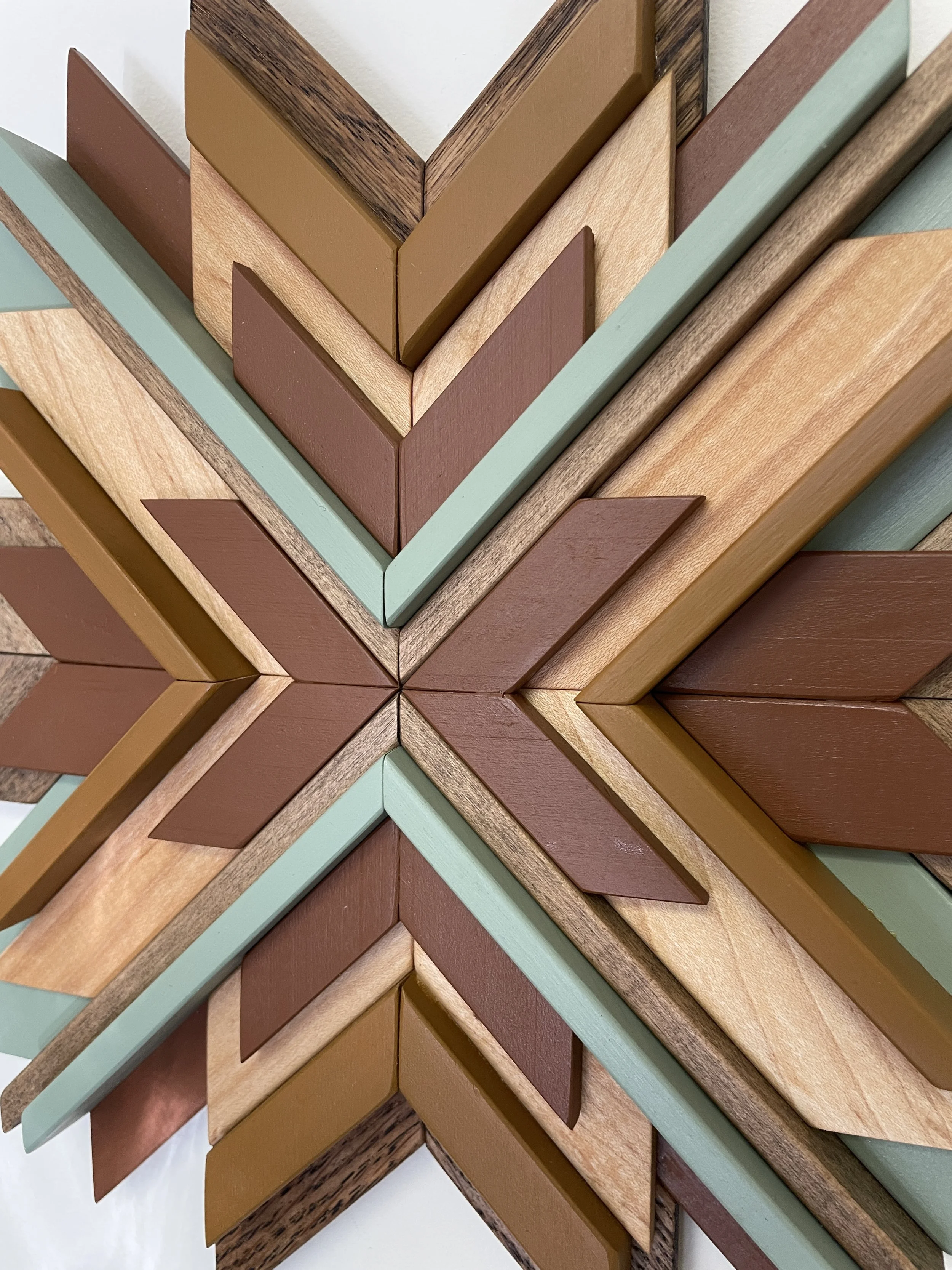 Detailed view of a handcrafted wooden sunburst mosaic in green, yellow, and orange paints with natural and espresso stains.