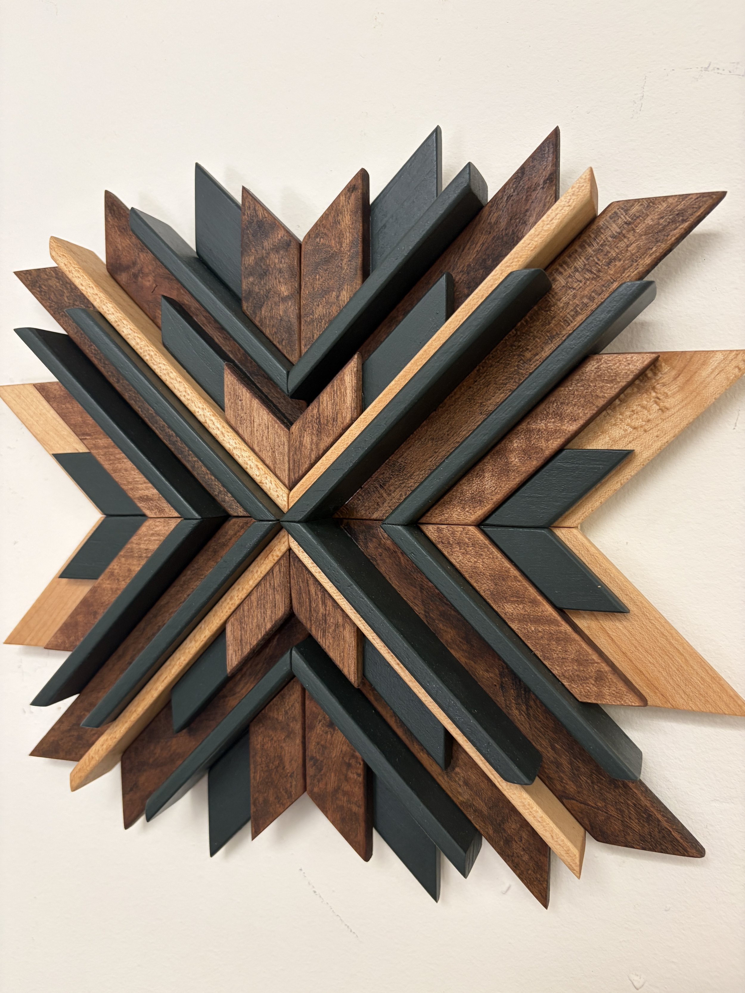 Angled view of a wooden sunburst style mosaic in green paint with light and dark stains.