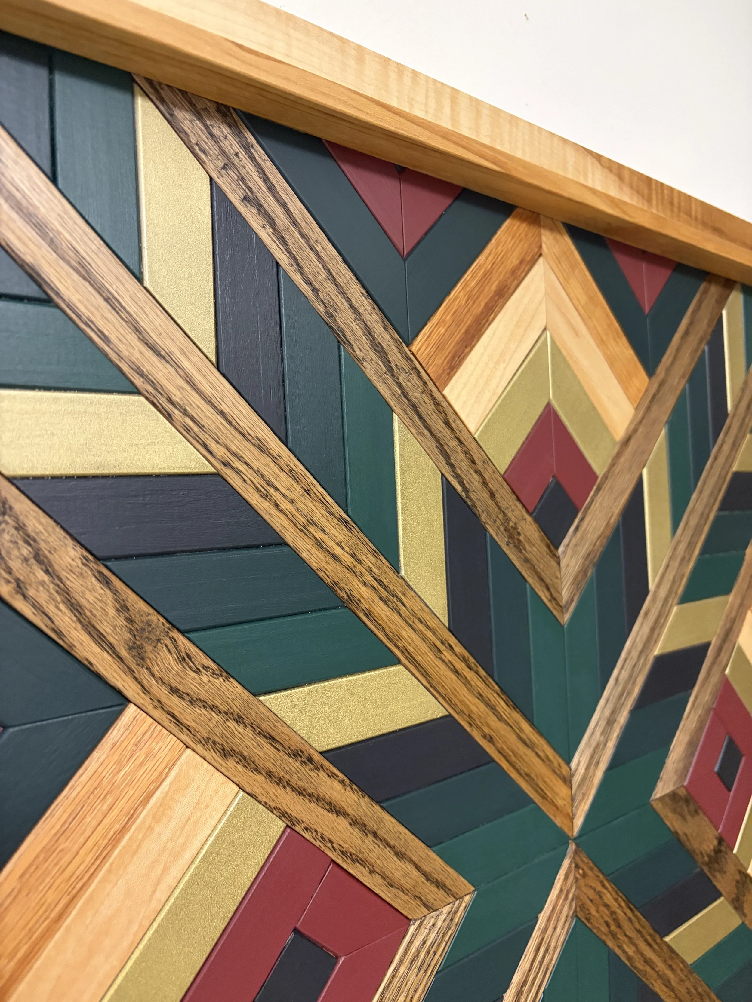 Side view of a handcrafted framed wooden mosaic in black, gold, maroon, teal, and green paint with natural and espresso stains.