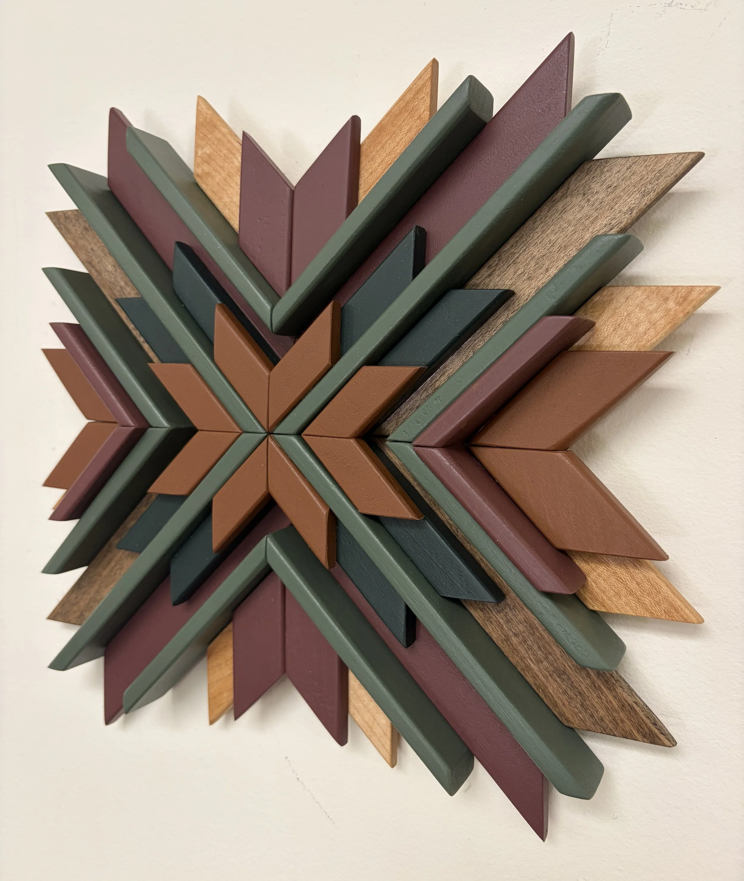 Wooden sunburst style mosaic in pink, orange, and green paint with natural and espresso stains.