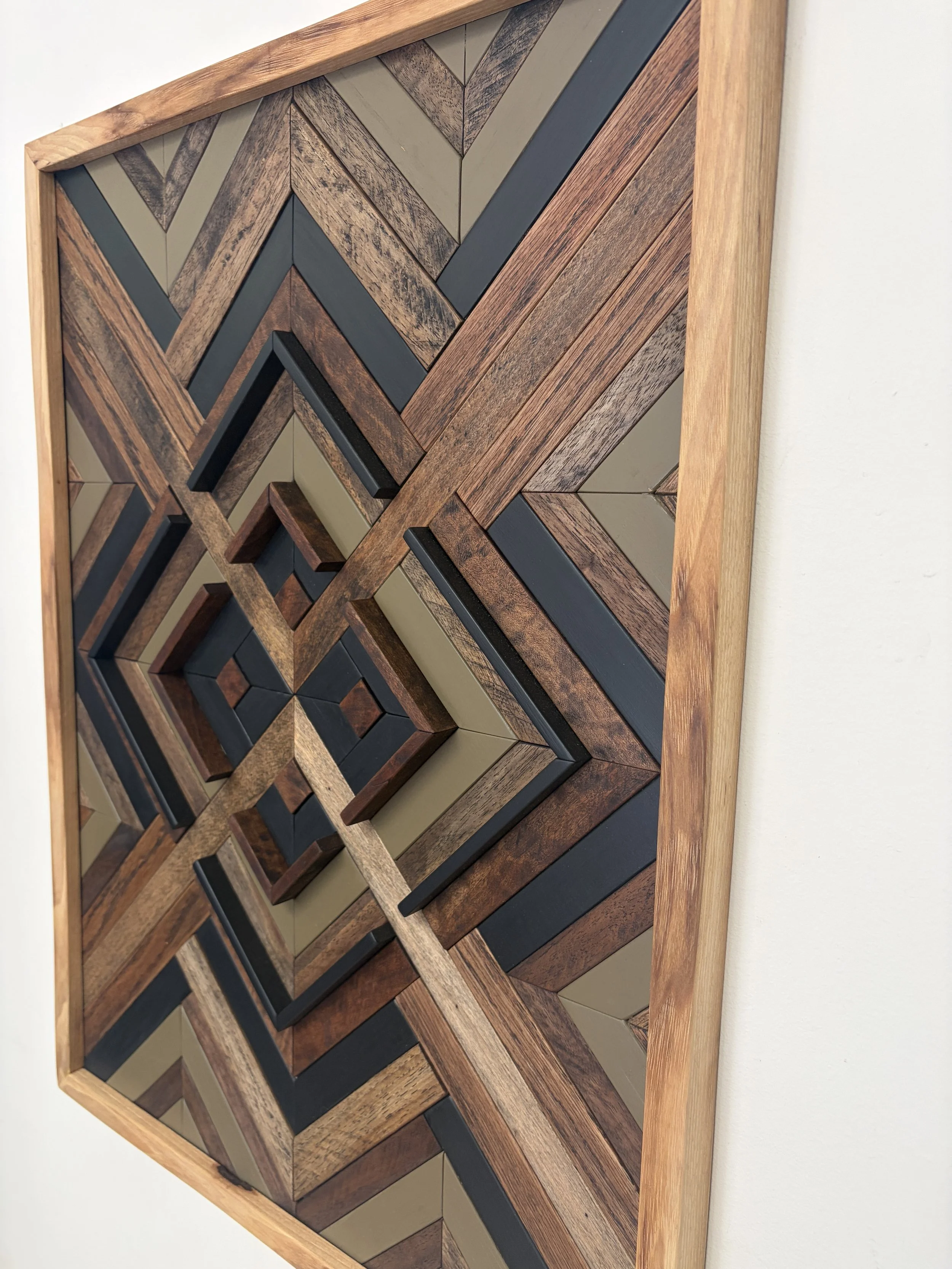 Side view of a handcrafted framed wooden mosaic in black and green paint with an espresso stains.