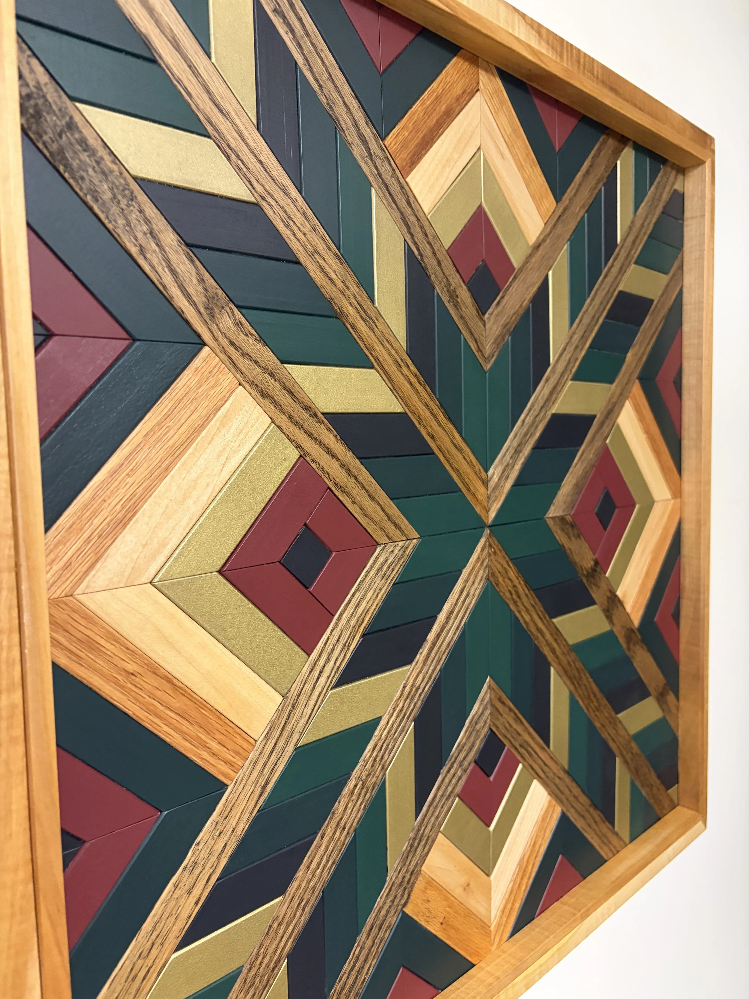 Angled view of a handcrafted framed wooden mosaic in black, gold, maroon, teal, and green paint with natural and espresso stains.