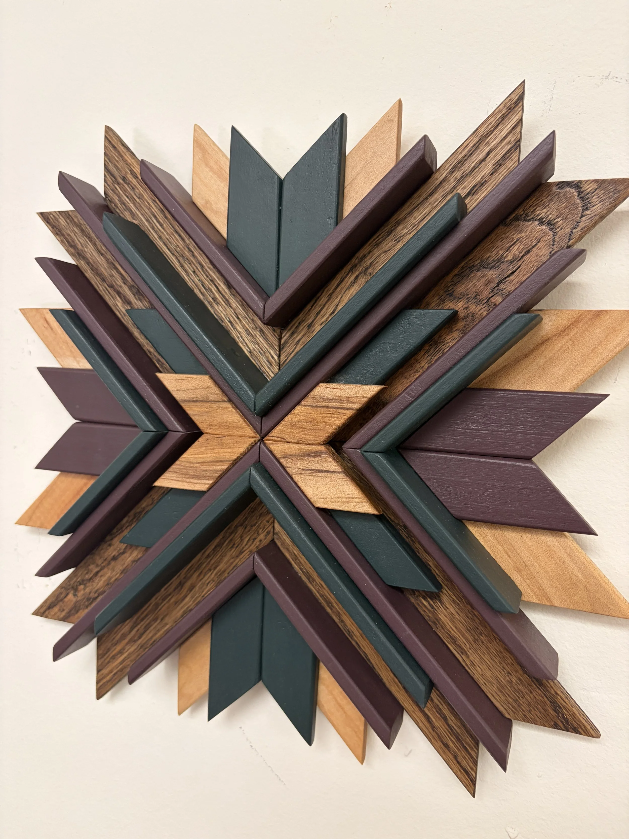 Angled view of a wooden sunburst style mosaic in green and purple paint with natural and espresso stains.