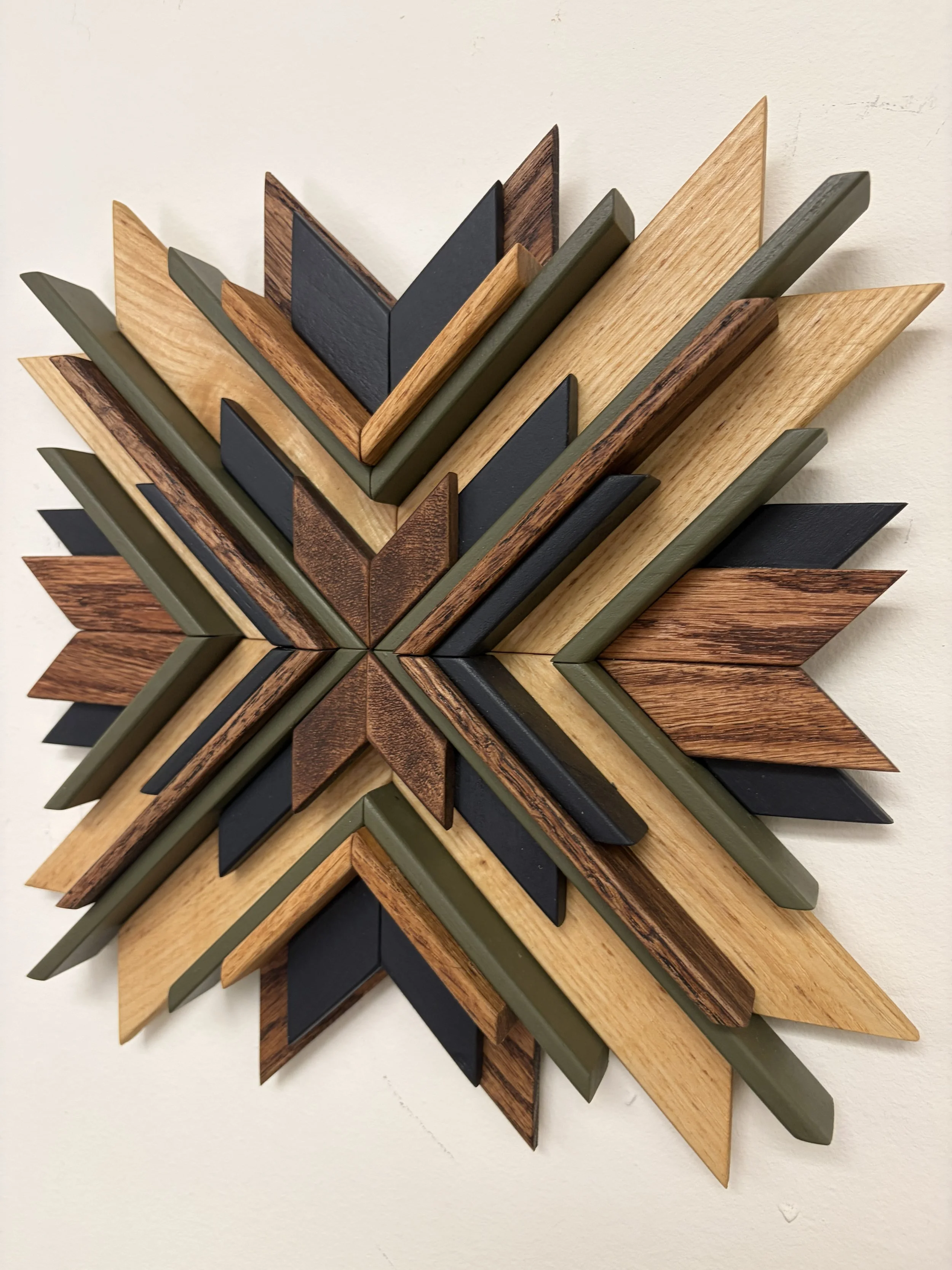 Side view of a wooden sunburst style mosaic in black and green paint with natural and espresso stains.