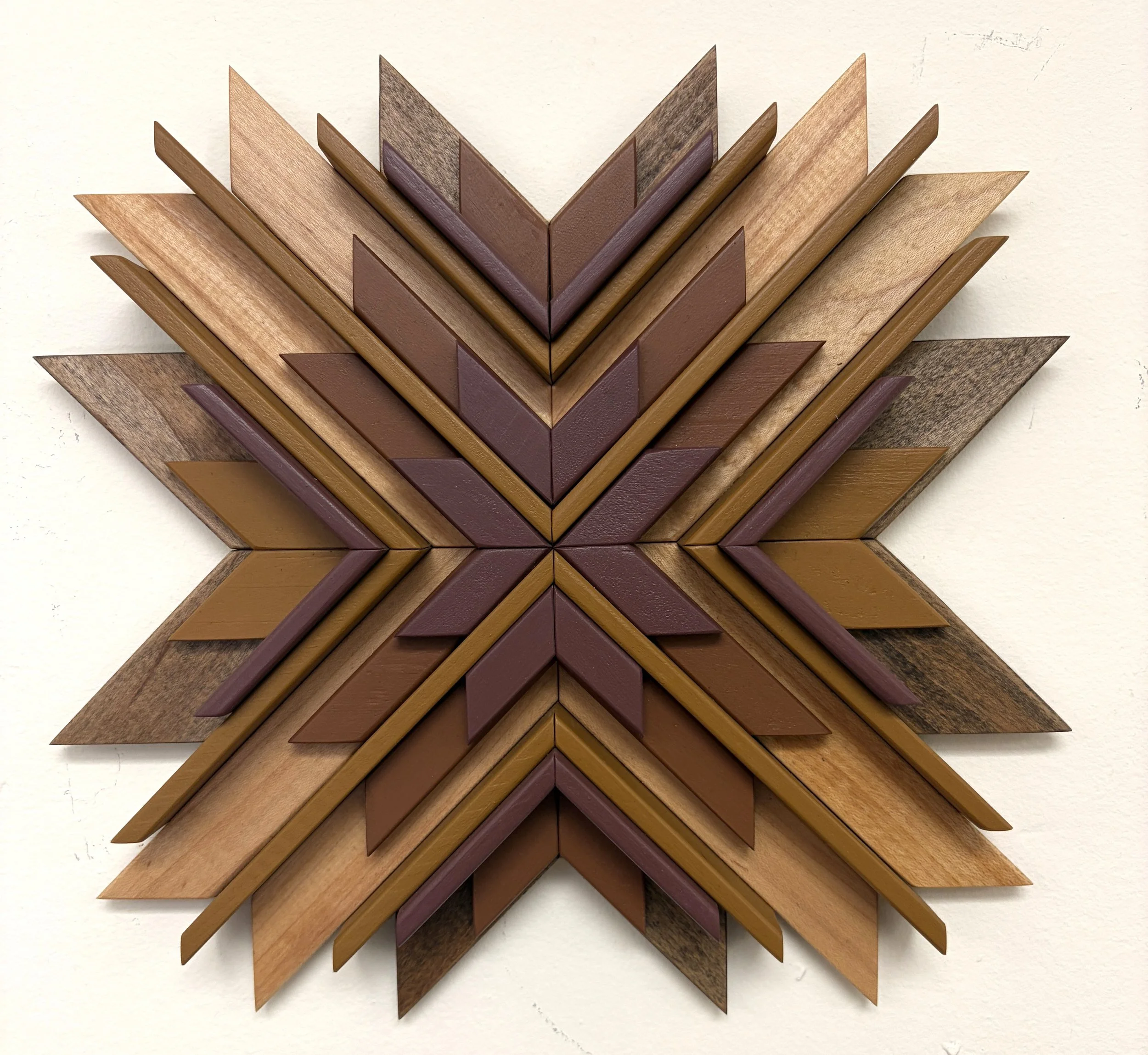 Wooden sunburst style mosaic in pink, orange, and yellow paint with natural and espresso wood stains.