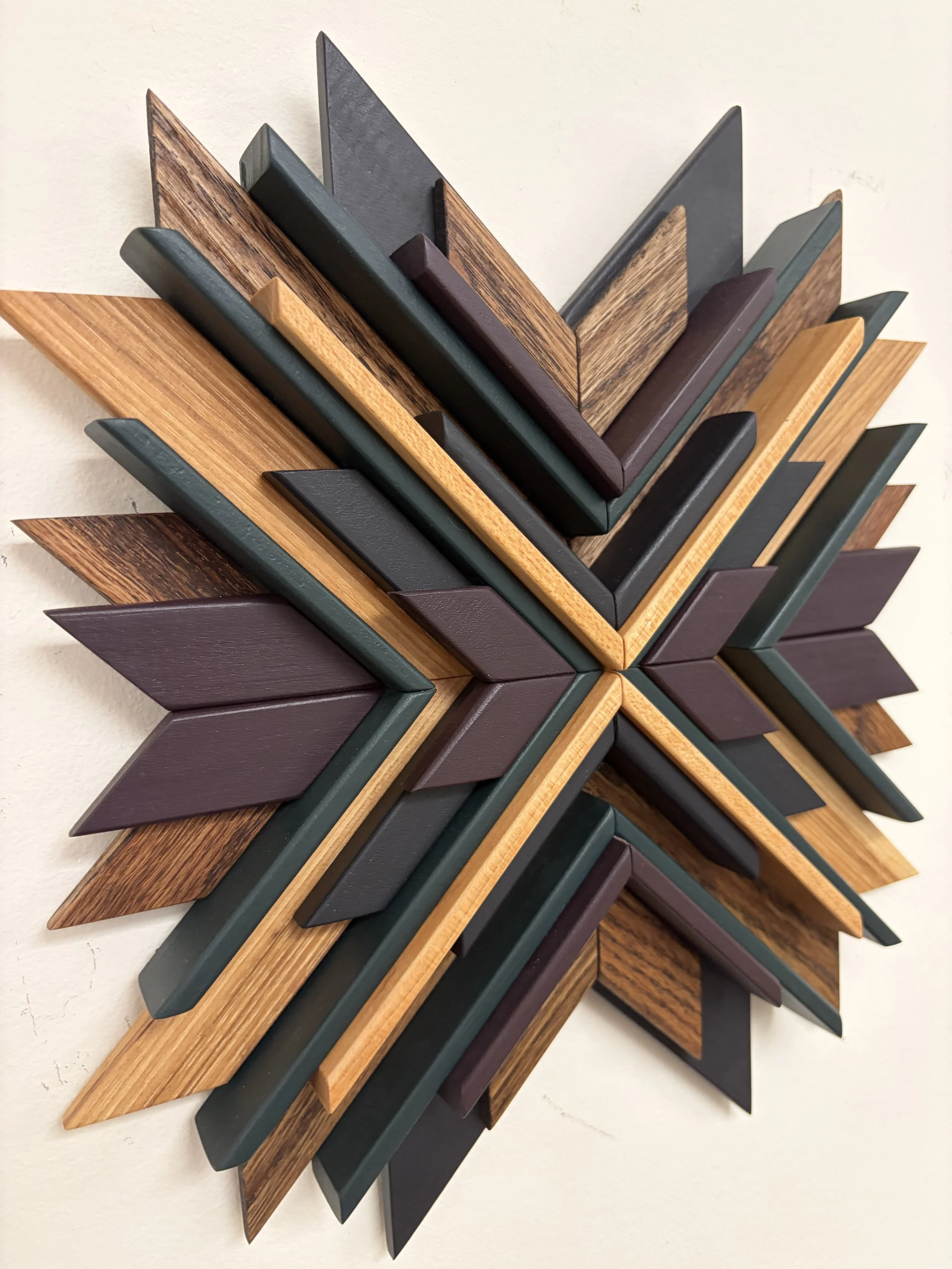 Angled view of a wooden mosaic in black, purple, and green paint with natural and espresso stains.