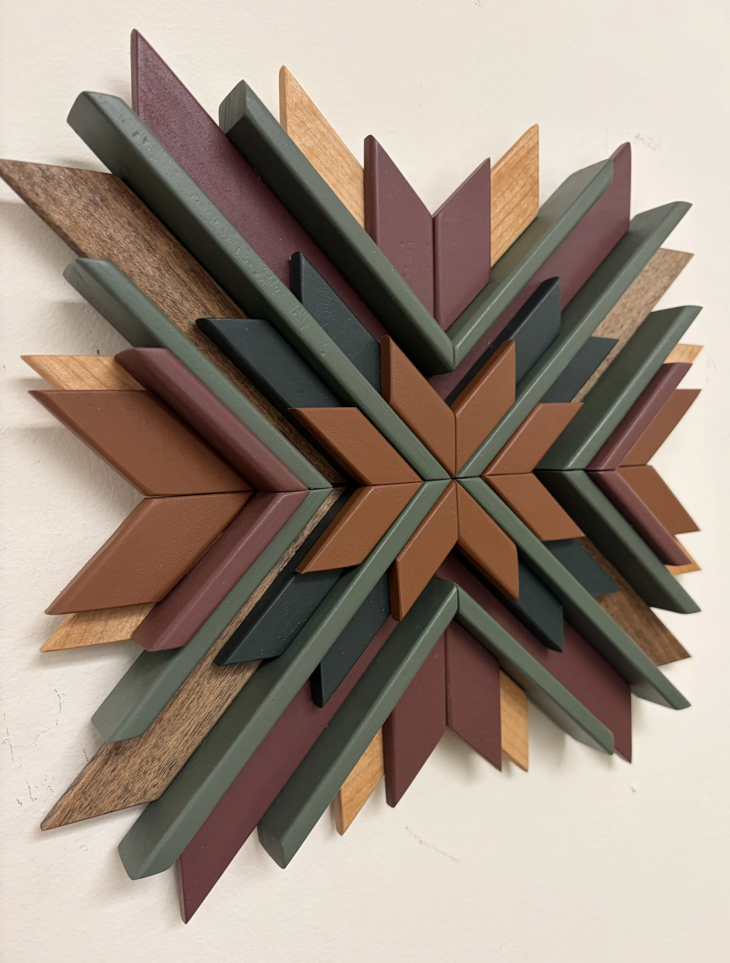Angled view of a wooden sunburst style mosaic in pink, orange, and green paint with natural and espresso stains.