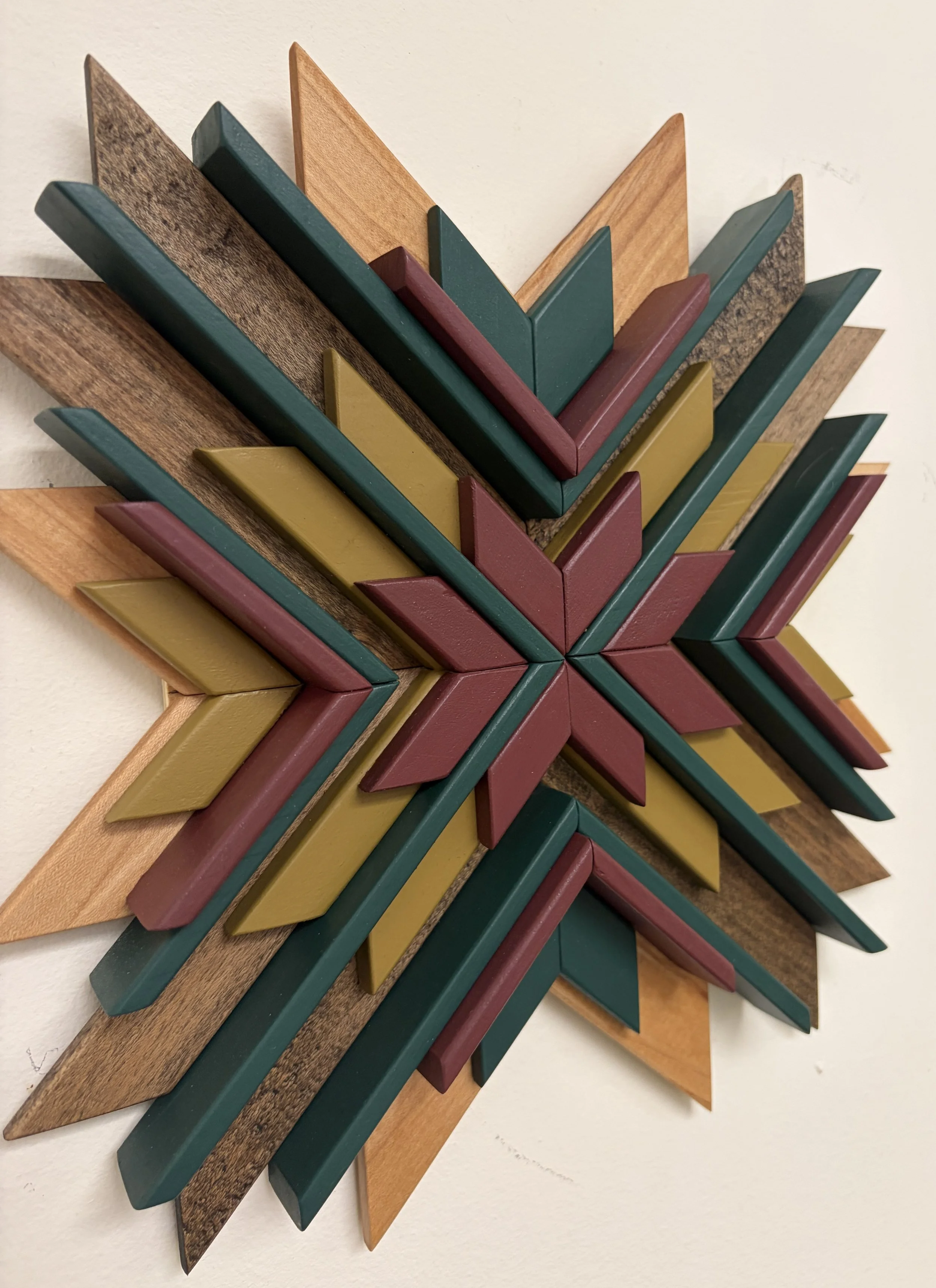 Side view of a sunburst style wooden mosaic in pink, teal, and bright green paint with natural and espresso stains.