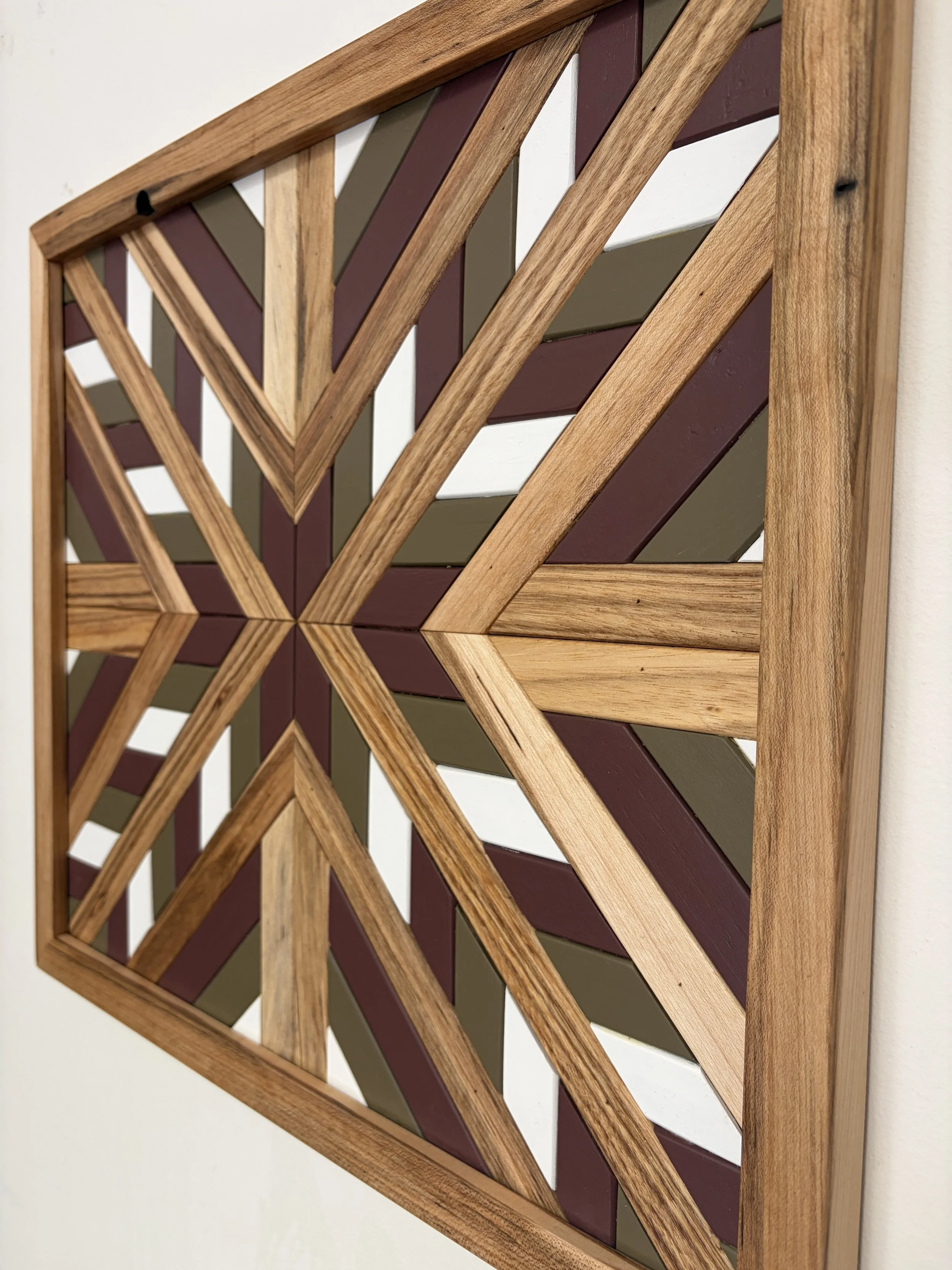 Side view of a handcrafted framed wooden mosaic in white, pink, and green paint with natural stains.