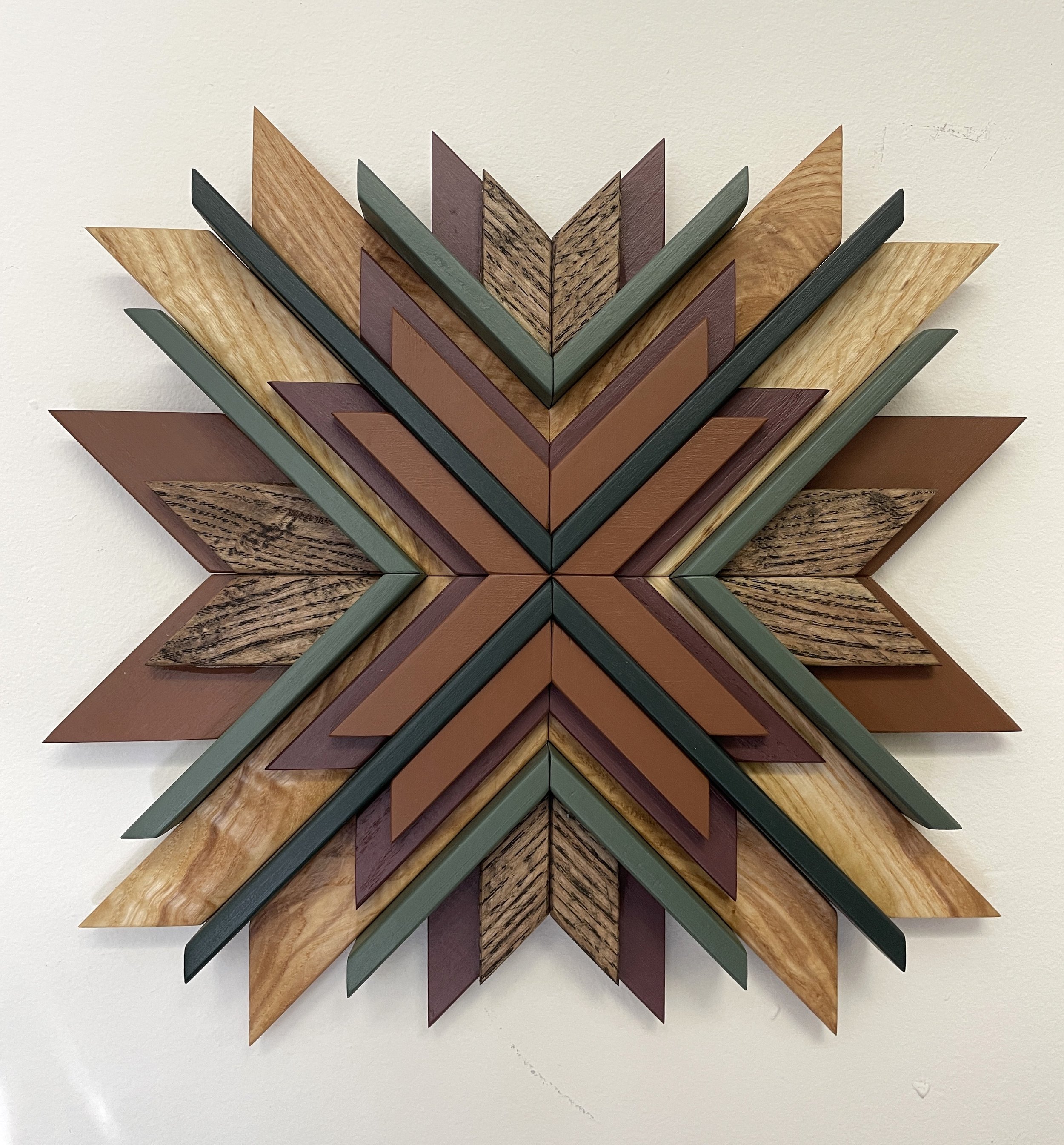 Handcrafted sunburst style wooden mosaic in pink, orange, and two  different green paints with natural and espresso stains.