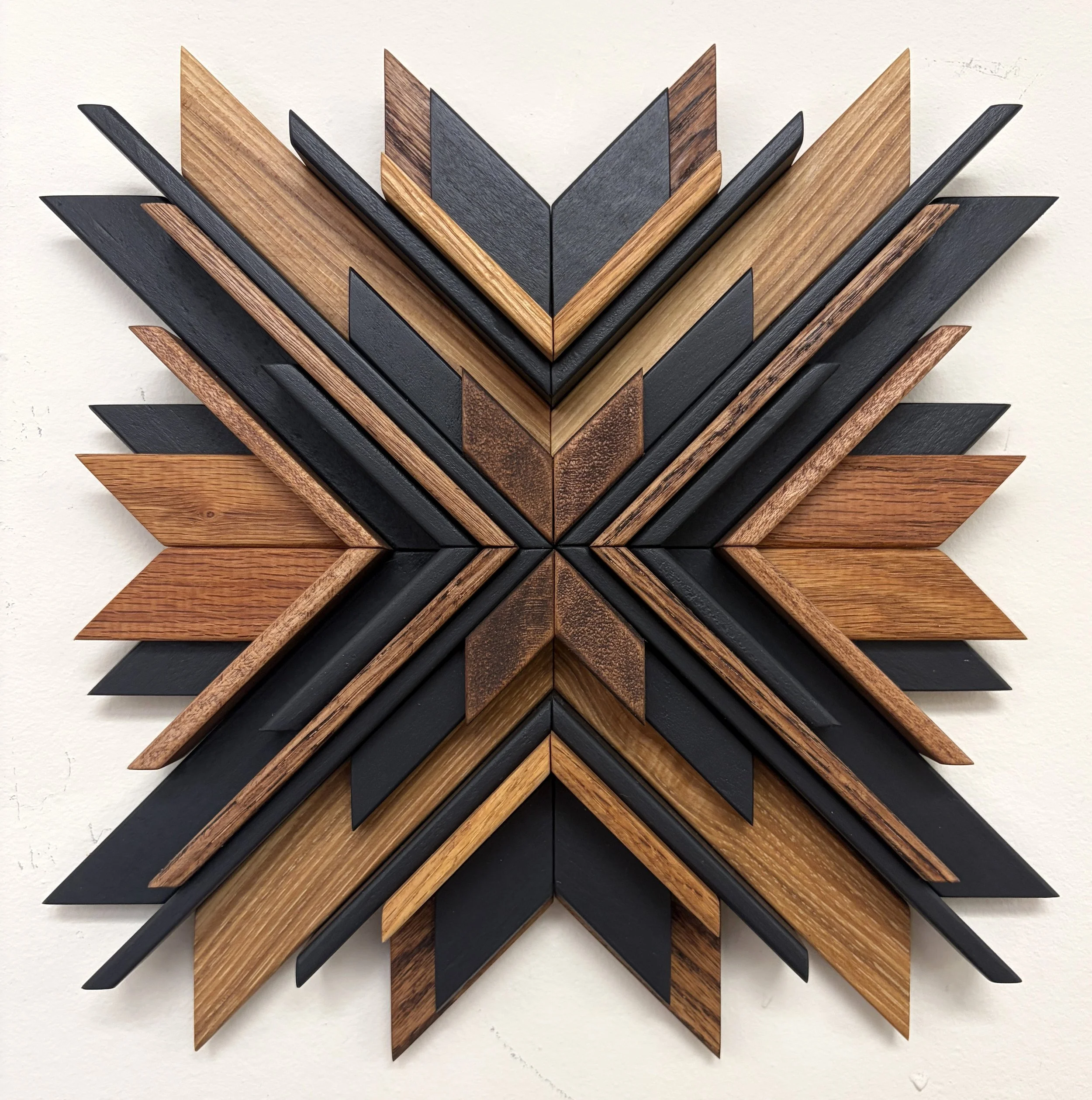 Wooden sunburst style mosaic in black paint with light and dark stains.