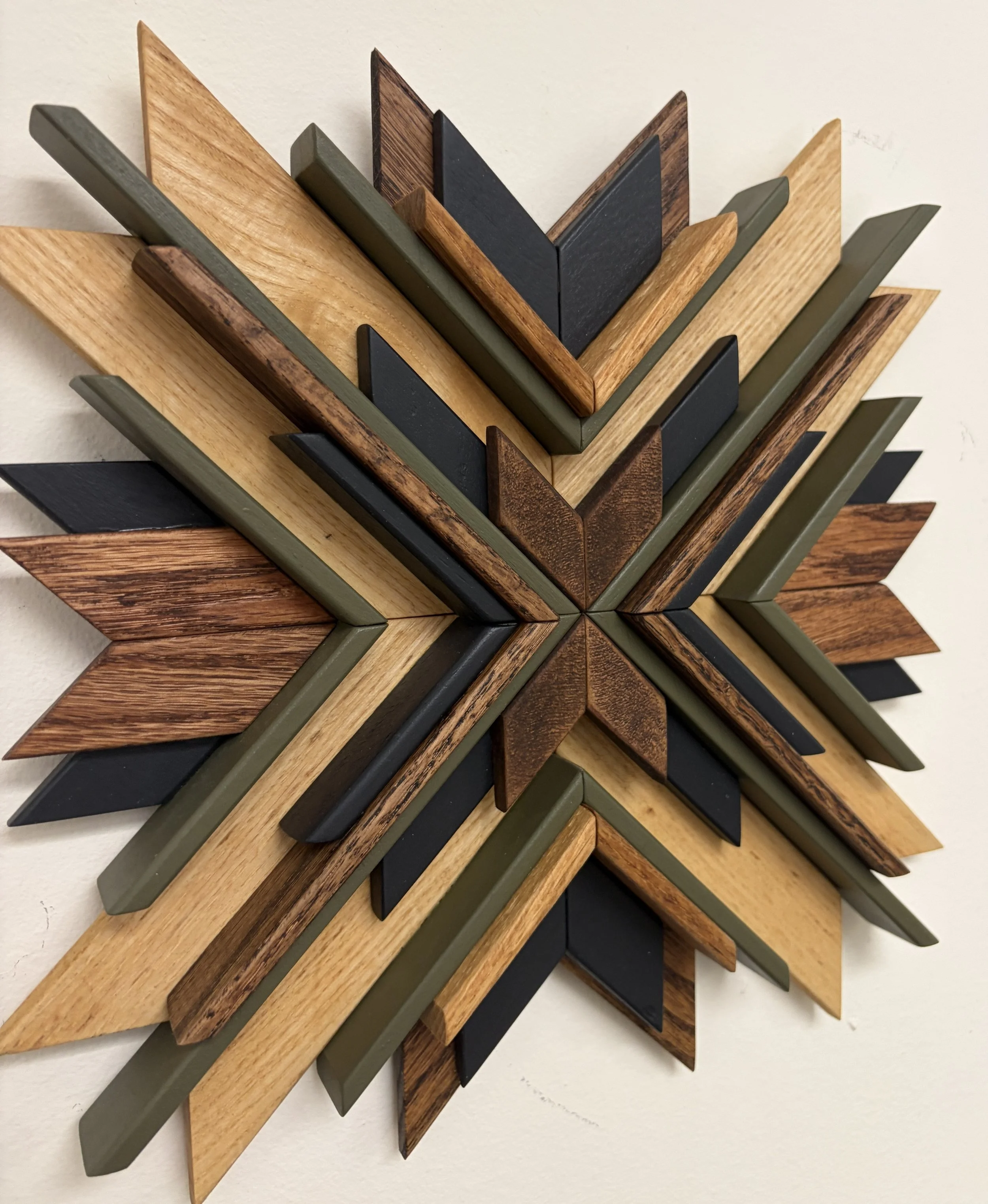 Angled view of a wooden sunburst style mosaic in black and green paint with natural and espresso stains.