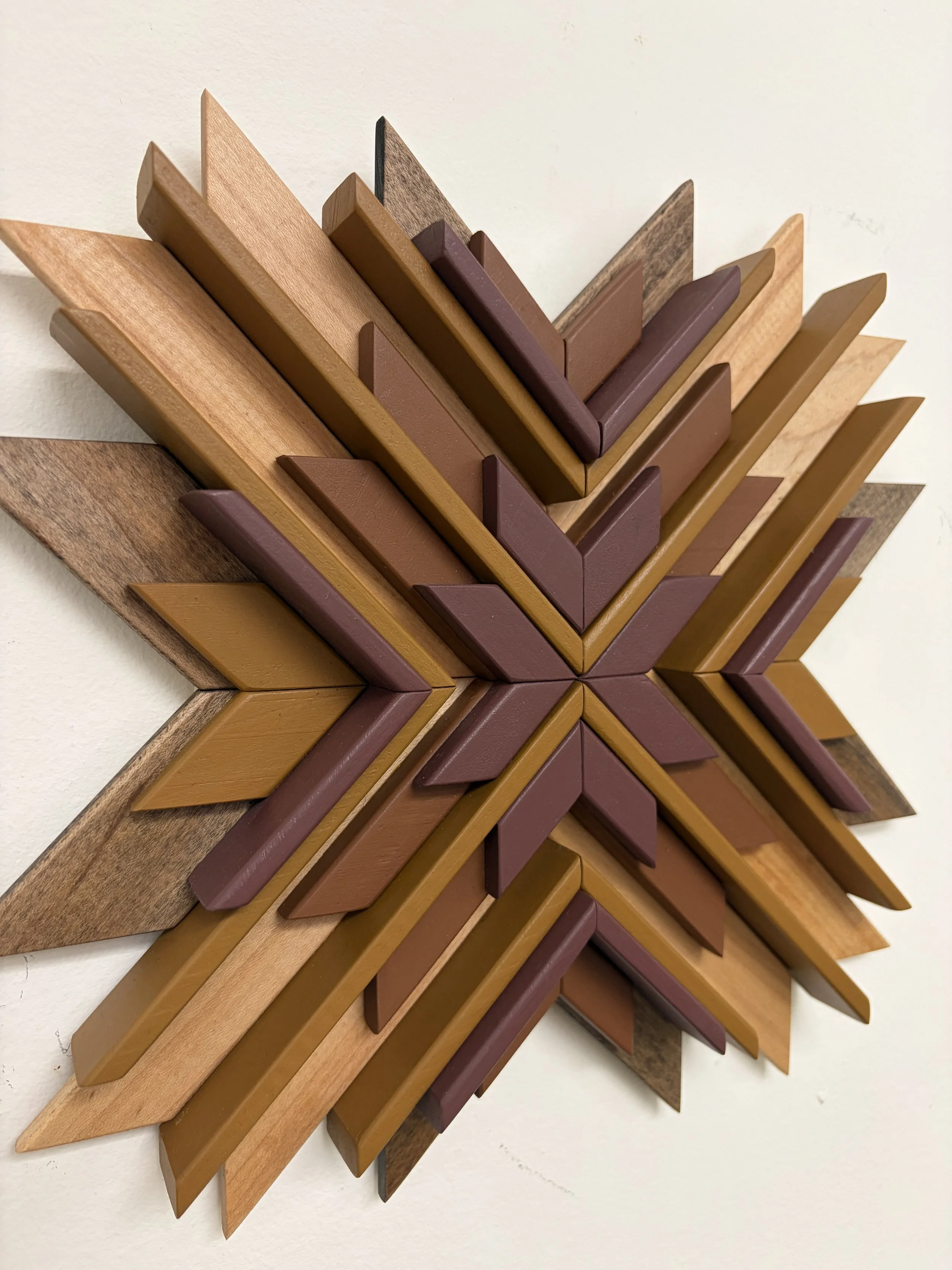 Side view of a wooden sunburst style mosaic in pink, orange, and yellow paint with natural and espresso wood stains.