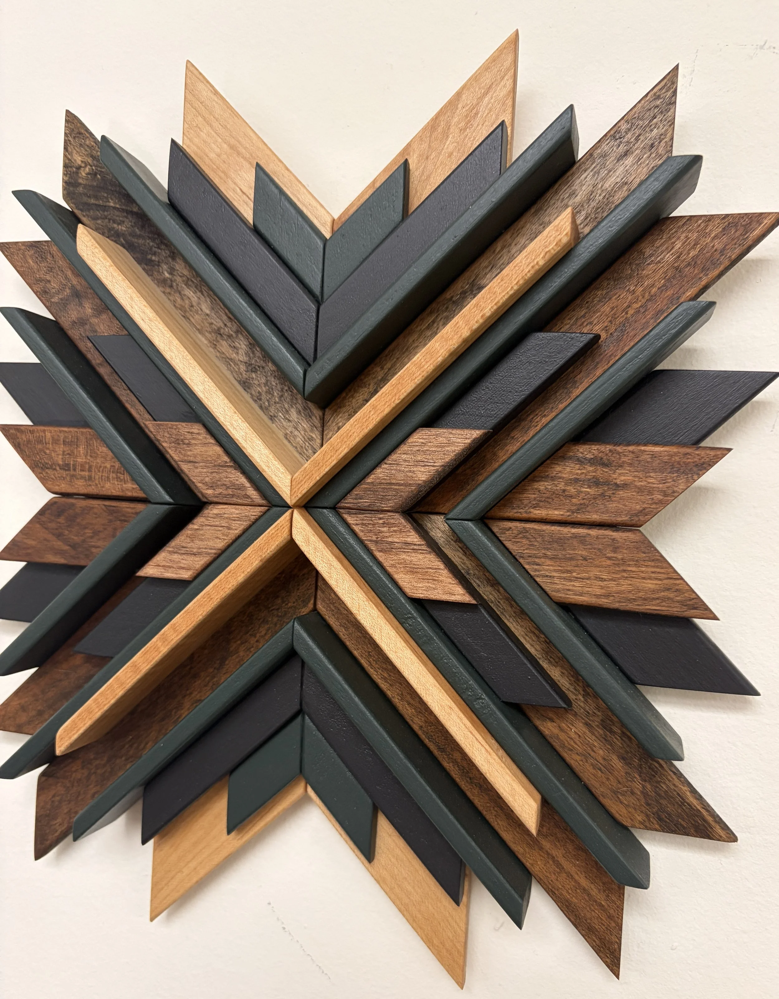 Side view of a wooden sunburst style mosaic in black and green paint with natural and espresso stains.