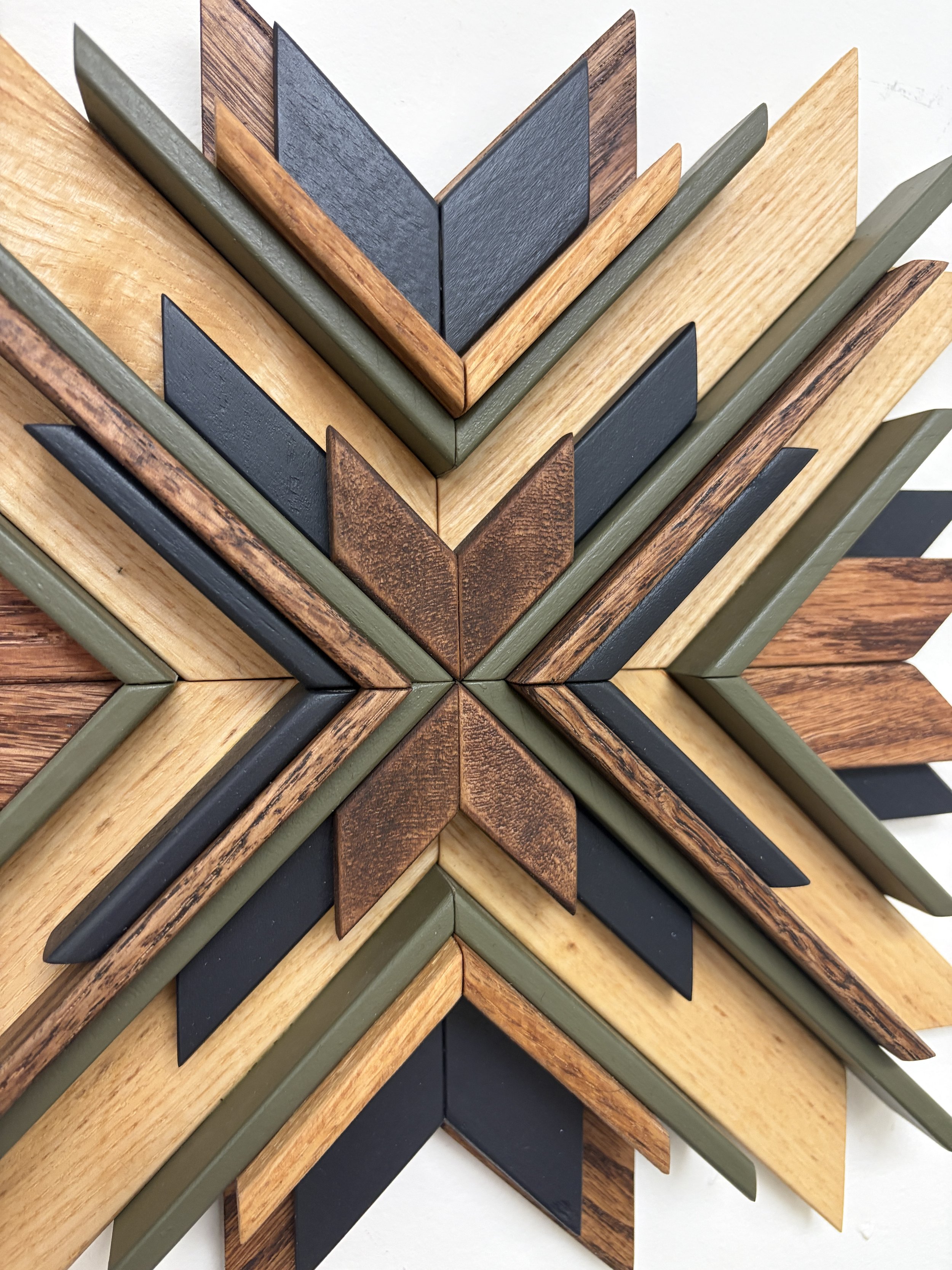 Close up view of a wooden sunburst style mosaic in black and green paint with natural and espresso stains.