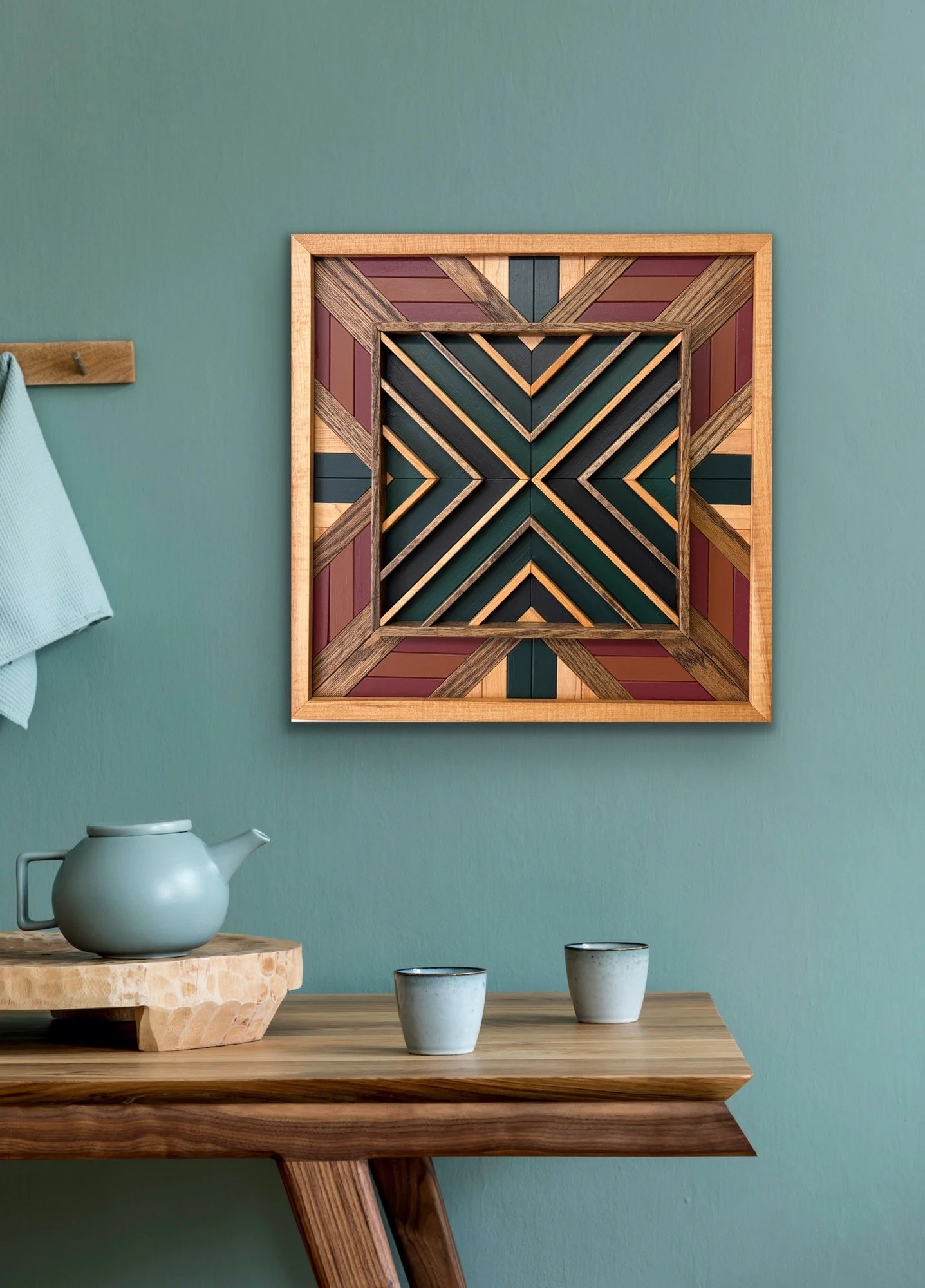 Handcrafted framed wooden mosaic in black, green, teal, pink, and orange paint with natural and espresso stains hanging on a wall.