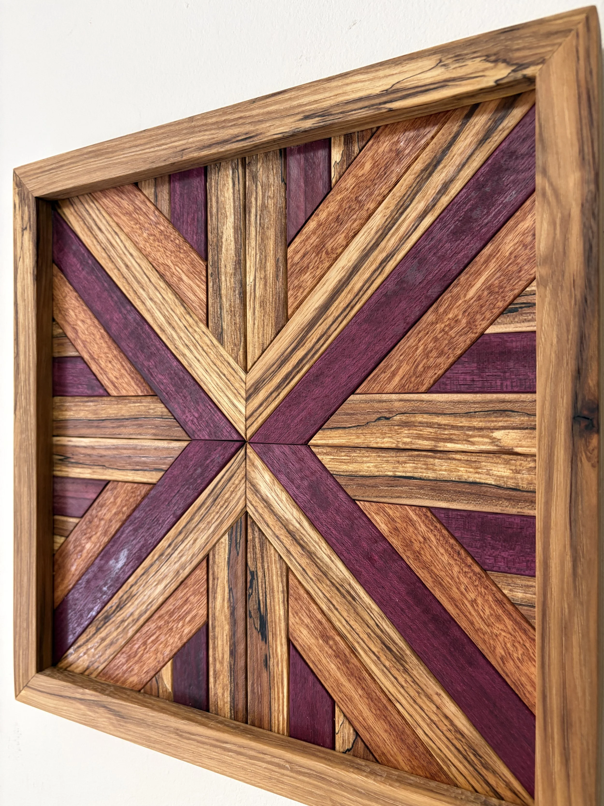 Angled view of a handcrafted framed wooden mosaic made from various exotic woods.