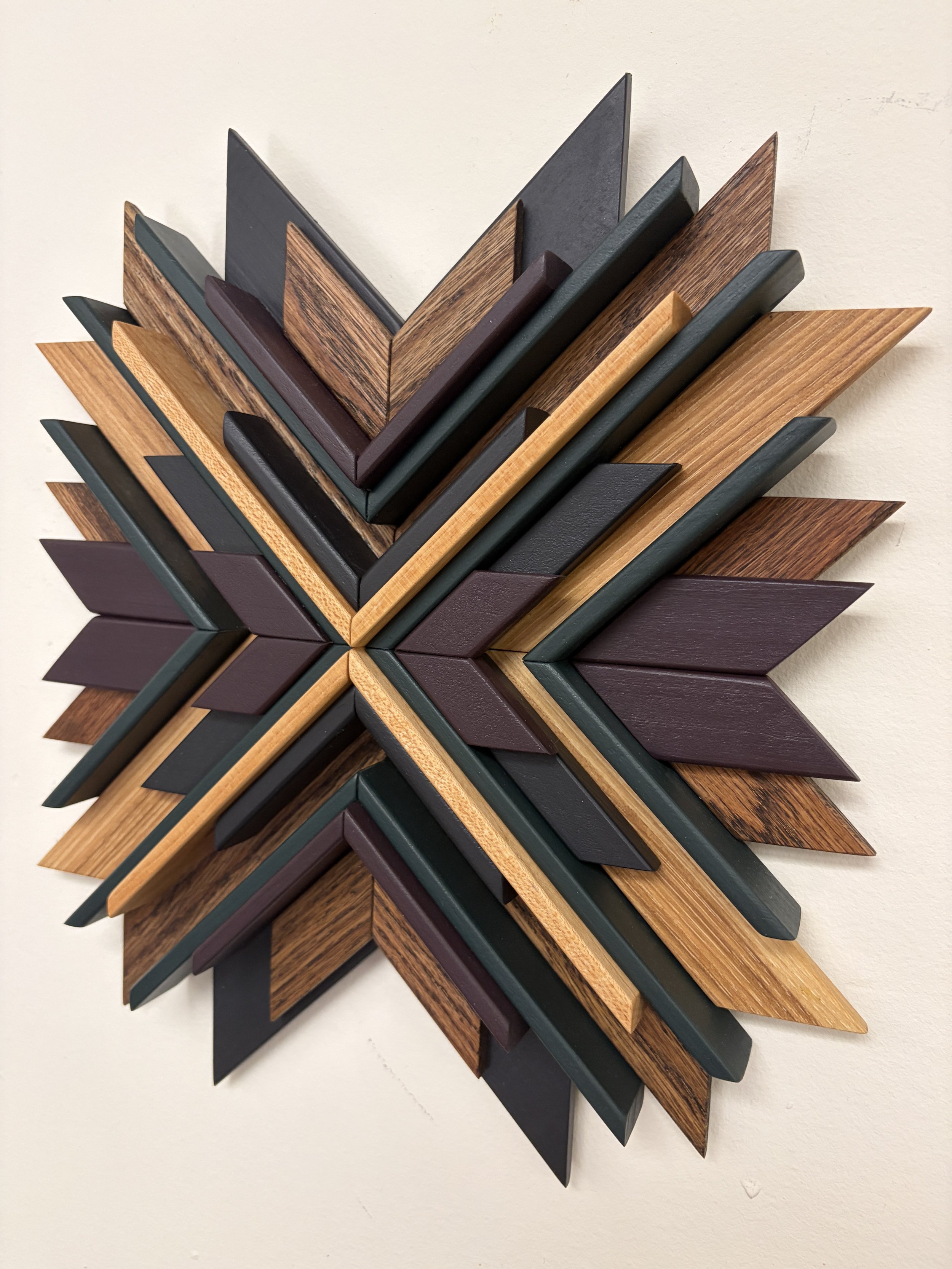 Side view of a wooden mosaic in black, purple, and green paint with natural and espresso stains.