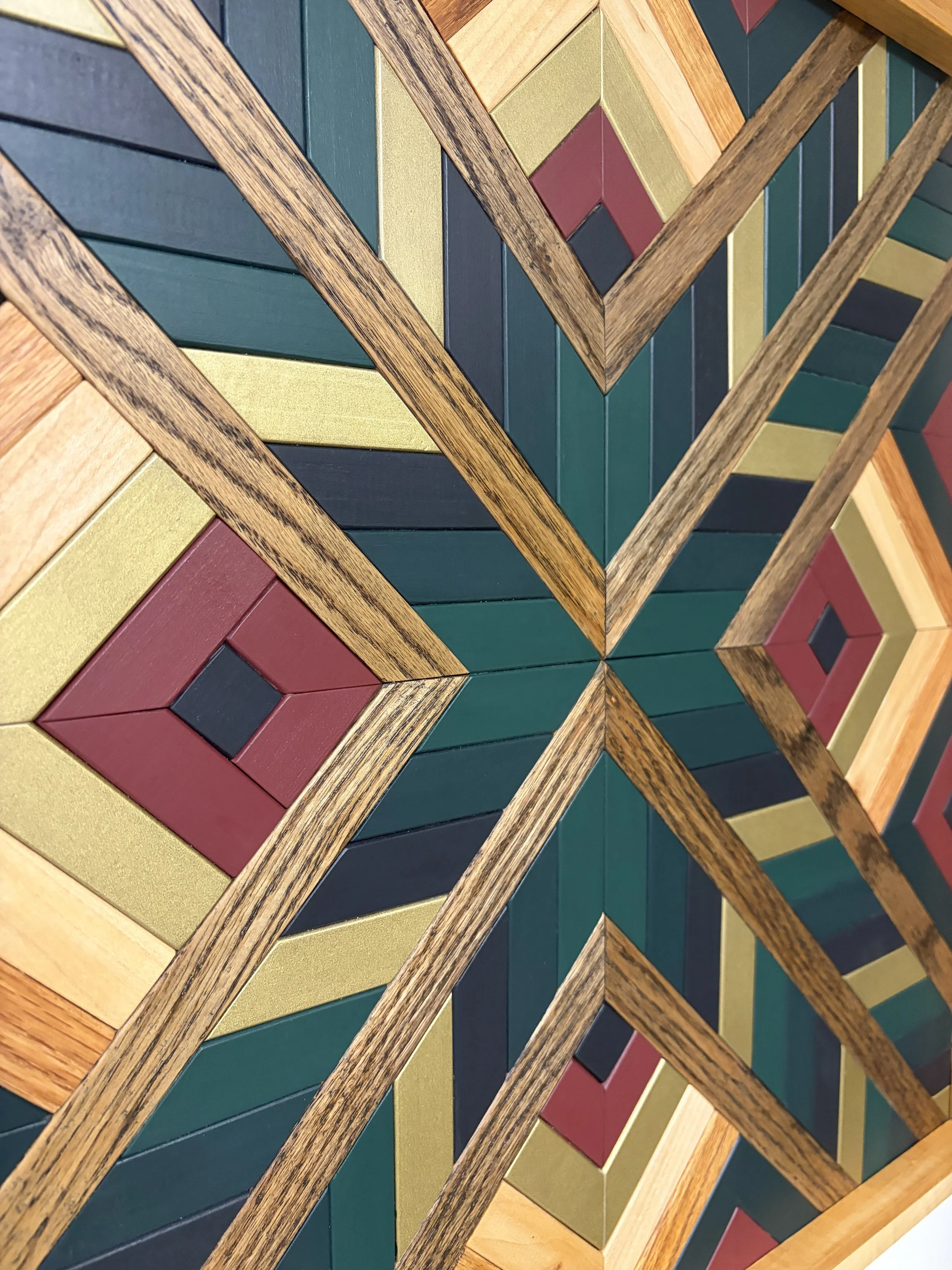 Detailed view of a handcrafted framed wooden mosaic in black, gold, maroon, teal, and green paint with natural and espresso stains.